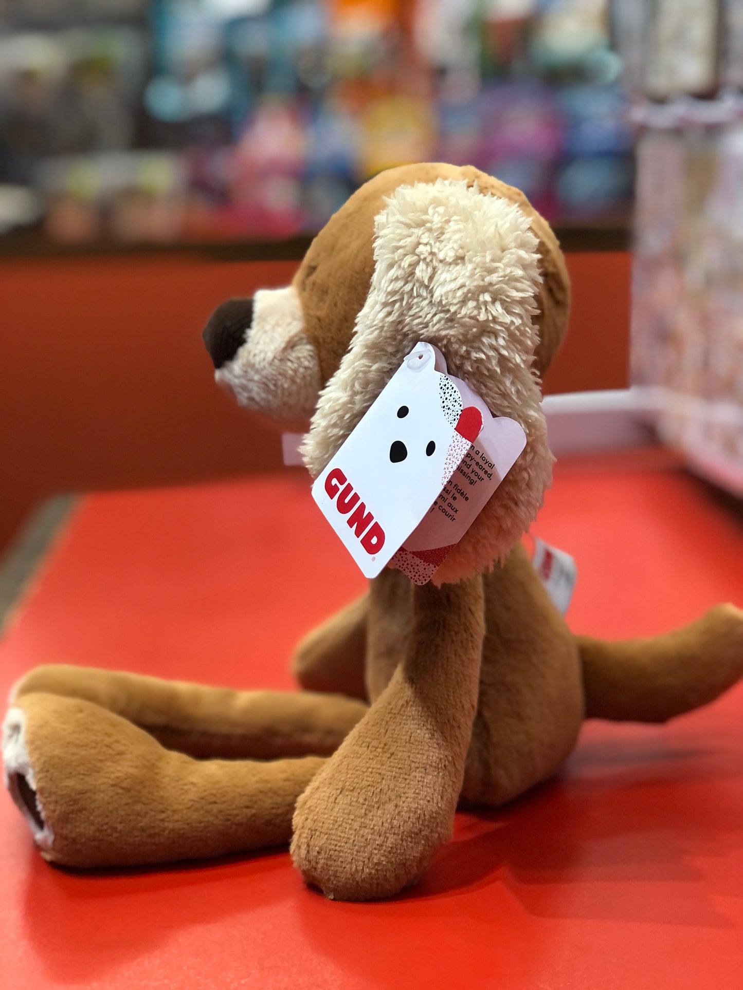 Gund Take-Along Masi 15" plush puppy with soft brown fur, floppy ears, and Gund tag, sitting on red surface