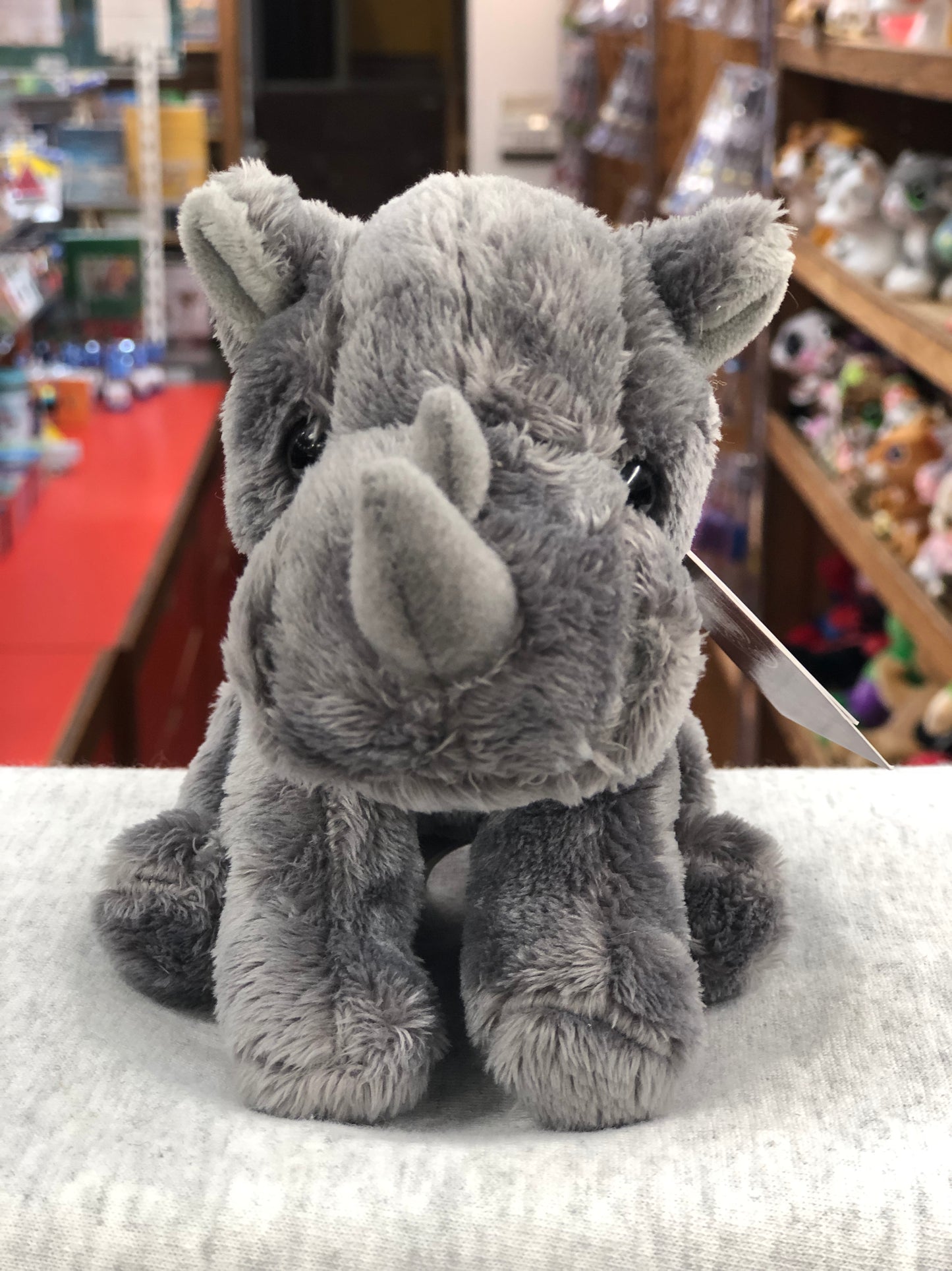 Soft gray Charlie Bears Cuddle Cub Rhino plush toy sitting on display, perfect size for baby's hands