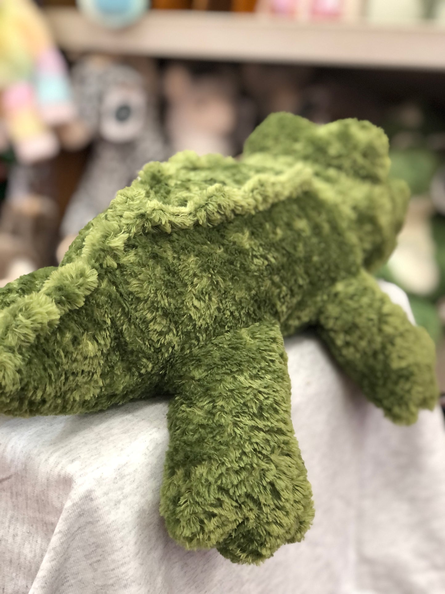 Soft, floppy green alligator plush toy on display, showcasing its huggable texture and playful design