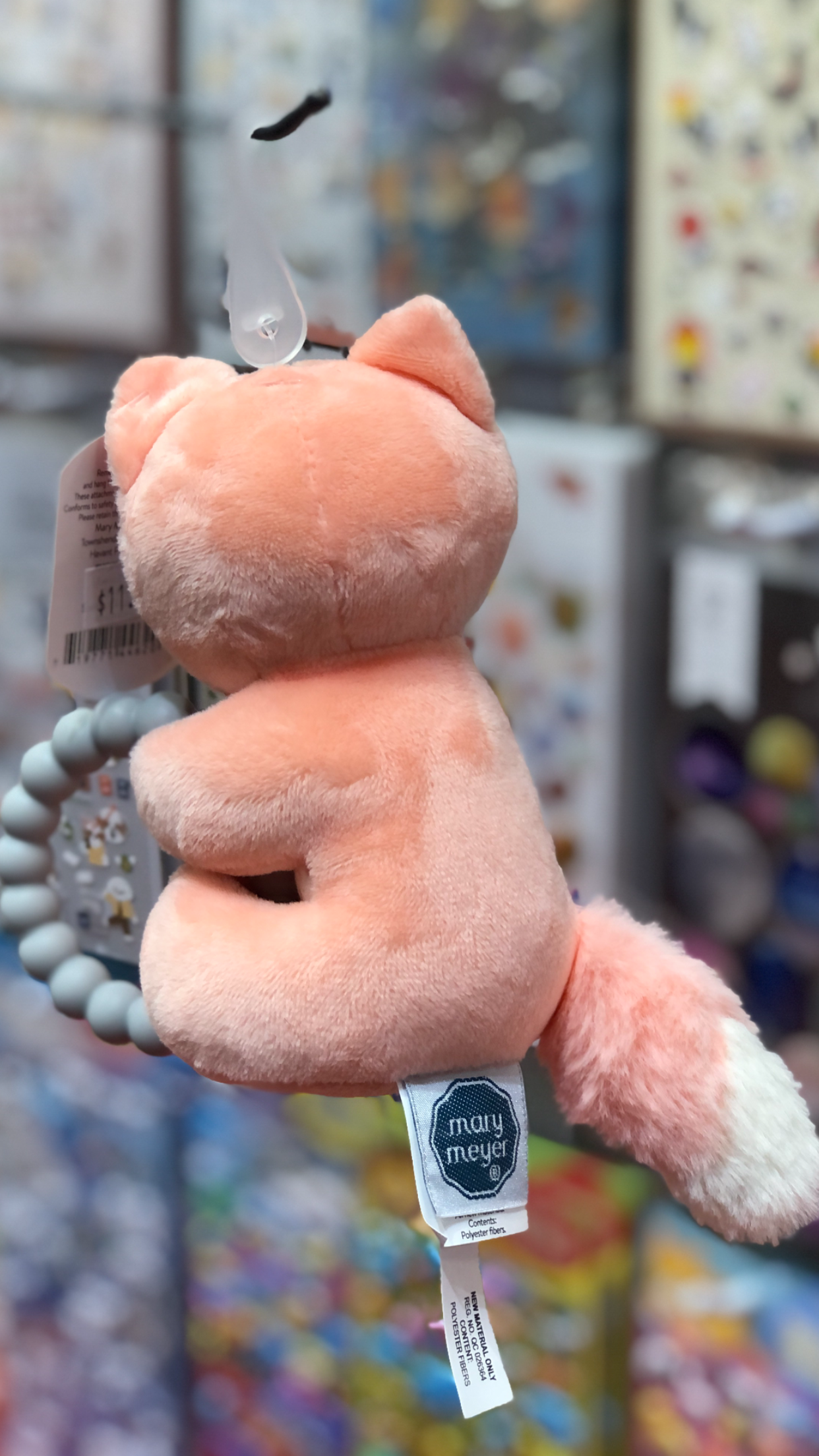 Soft pink Mary Meyer fox teether rattle with silicone teether and beaded loop, displayed in toy store setting