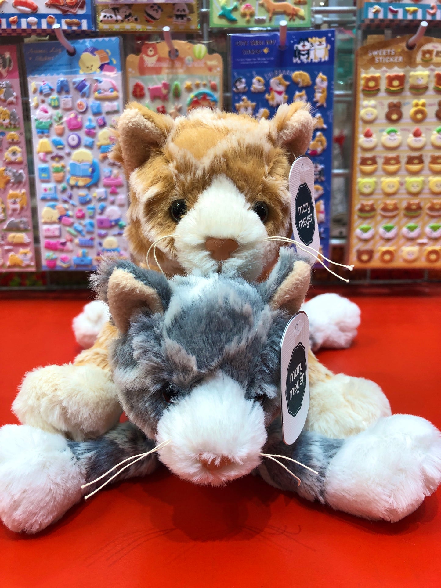 Soft, textured Mary Meyer FabFuzz Waffles Kitten plush toys in orange and gray, displayed in toy store with colorful stickers