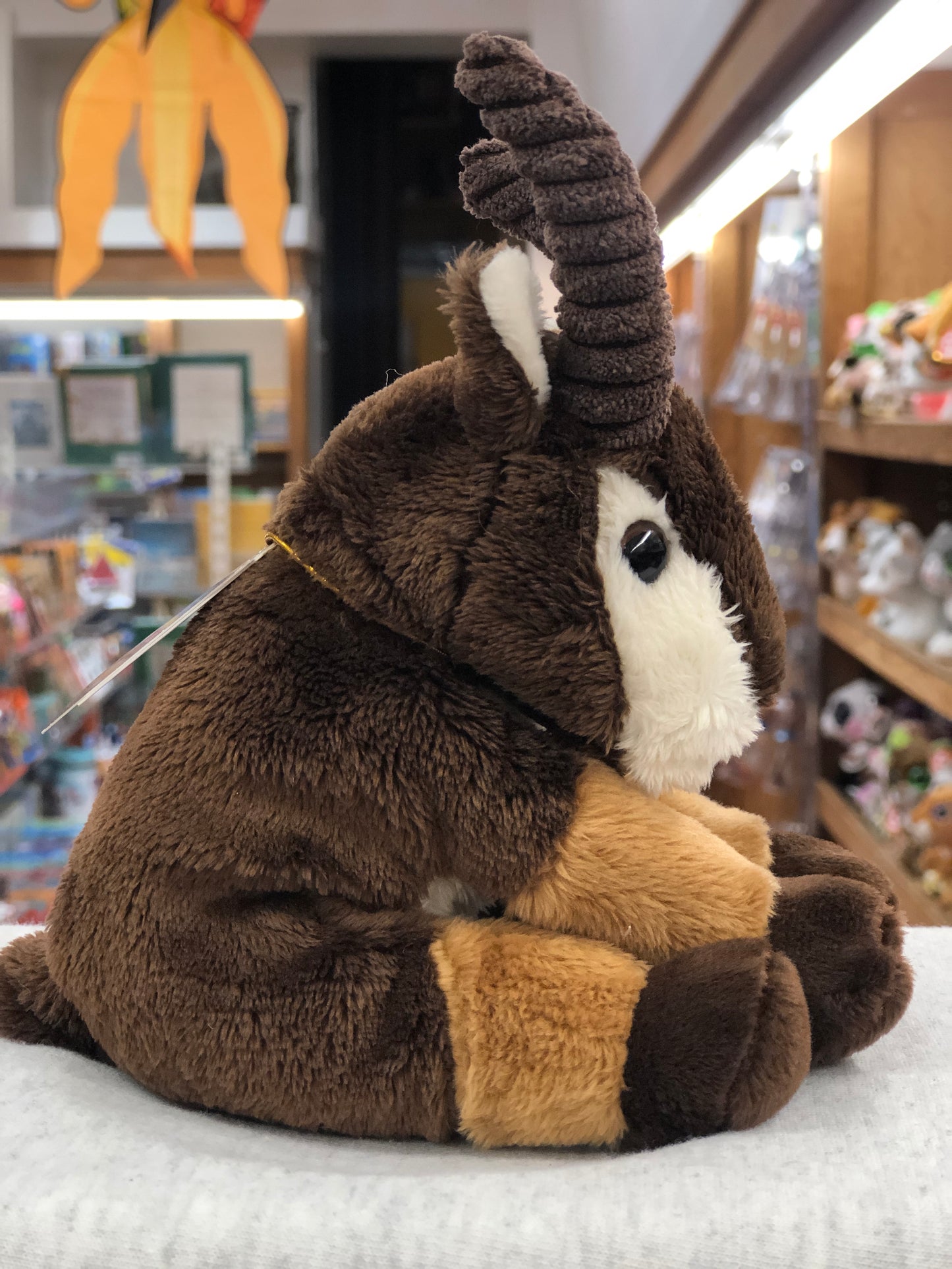Soft, cuddly Charlie Bears mountain goat plush toy with curled horns, perfect for babies, displayed in a toy store