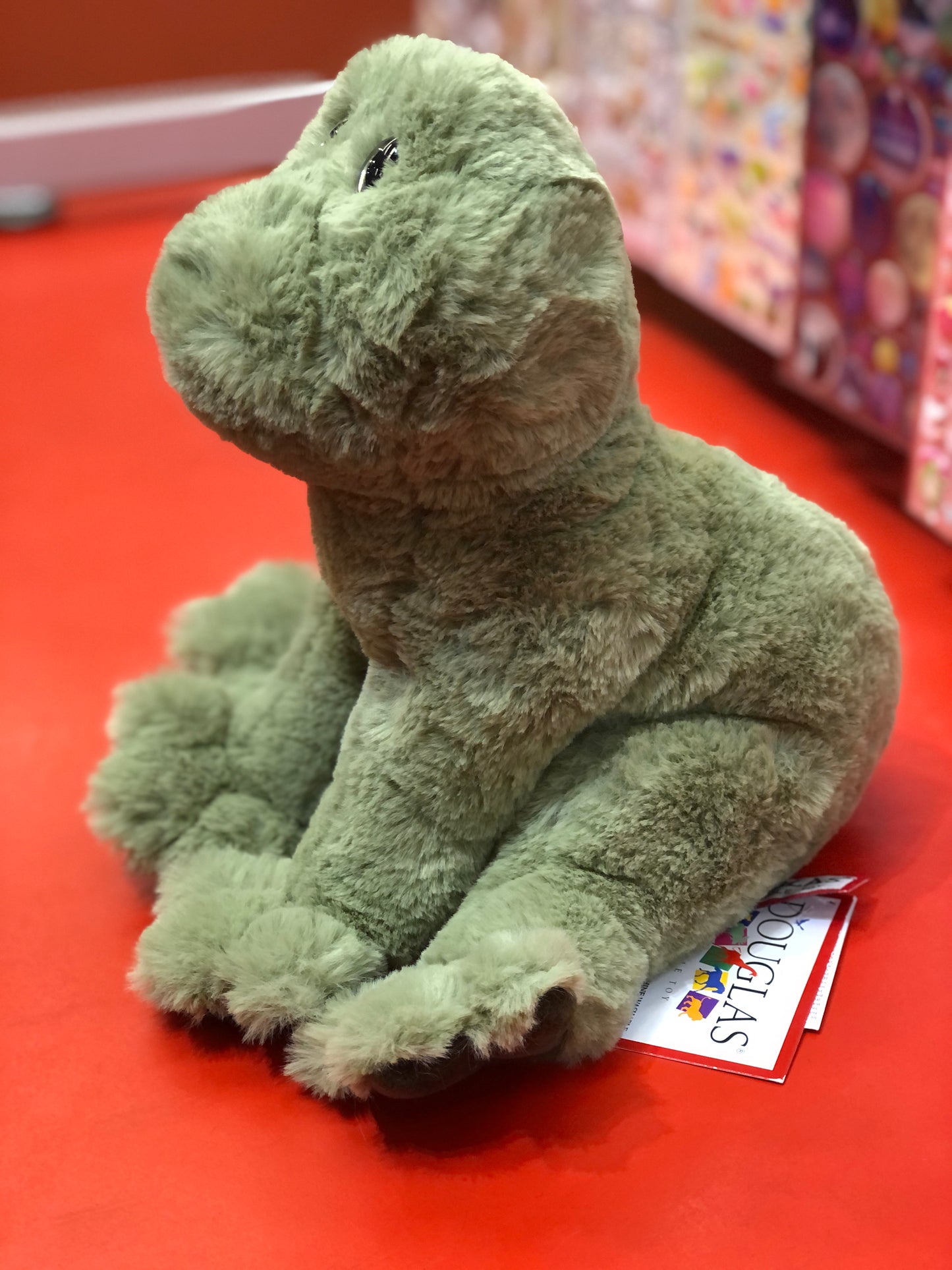 Soft green plush frog toy Finnie sitting on red surface, floppy body with beans and polyester fill, 8-inch size