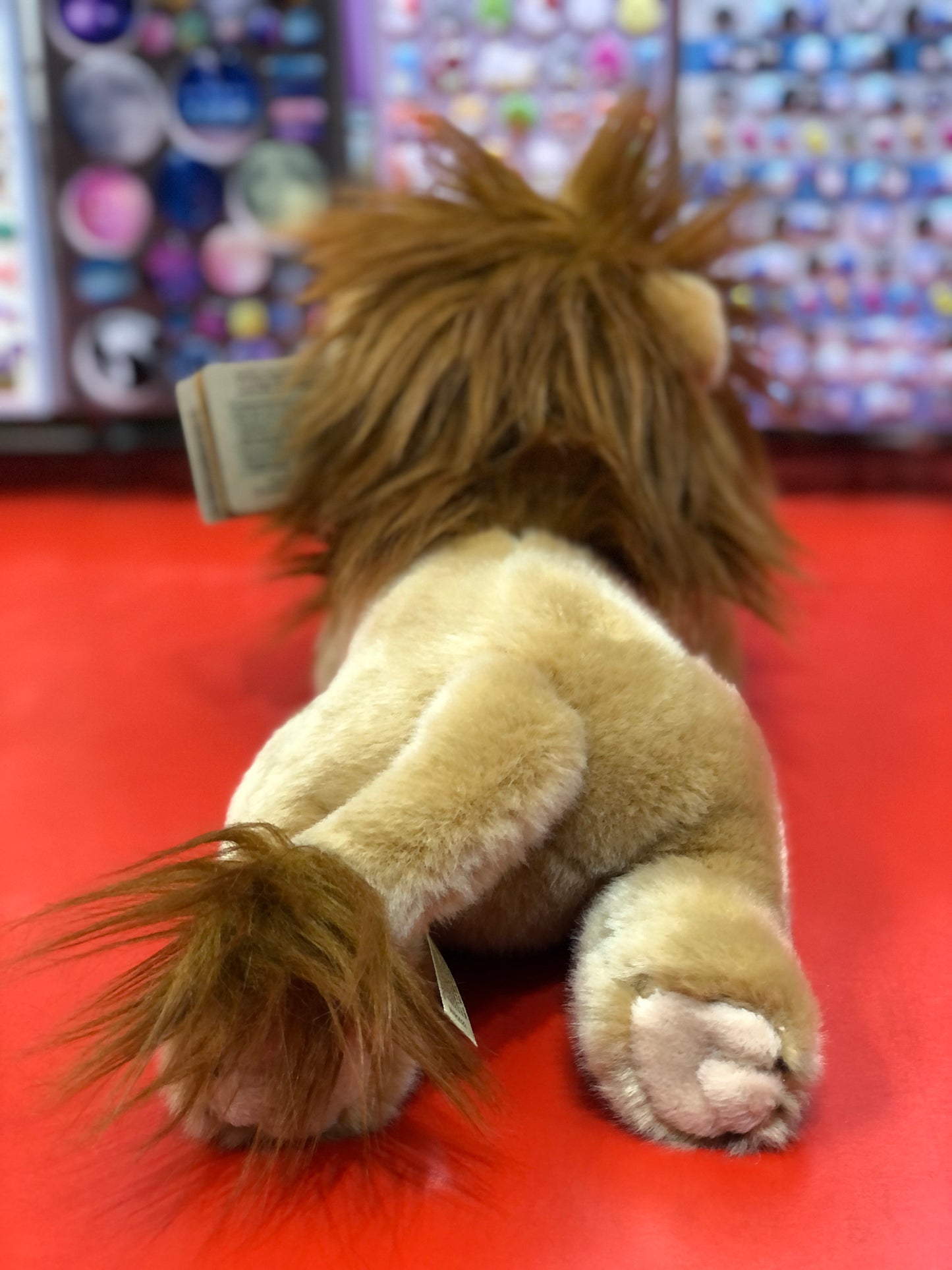 Aurora Miyoni plush lion with fluffy mane on red display, showcasing soft fur and cute details for ages 2+