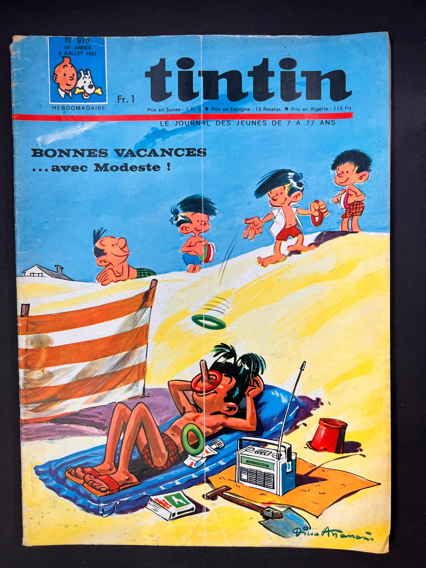 Tintin magazine cover: Modeste relaxing on beach, kids playing ring toss with his nose. Vintage comic from 1967, showing wear.
