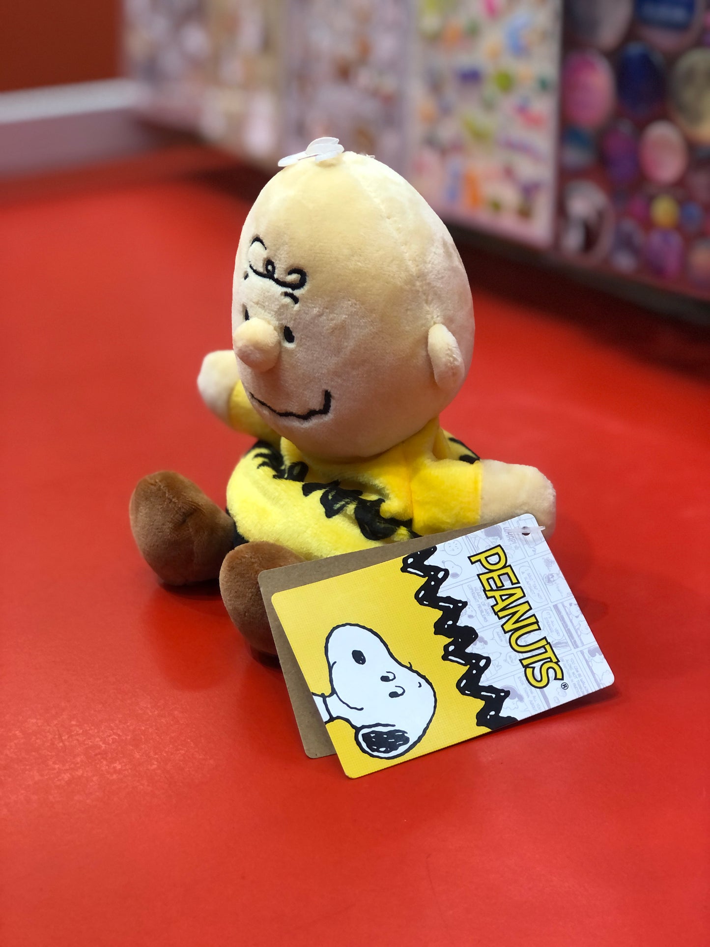 Aurora Peanuts Charlie Brown plush toy sitting on red surface with character tag, part of Palm Pals collection