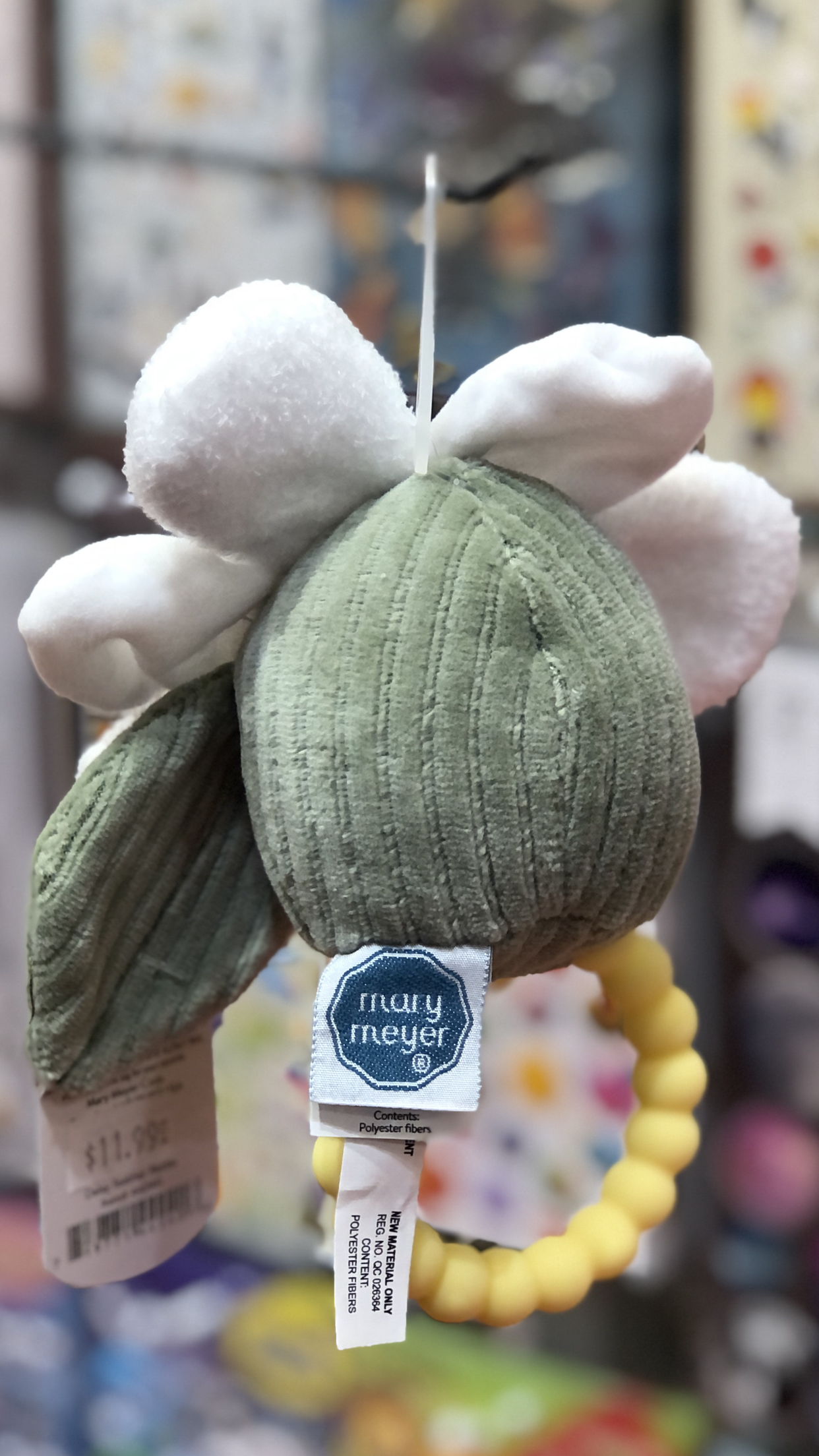 Mary Meyer Baby Soothie Daisy teether rattle with soft green plush body, white petals, and yellow ring handle for soothing sore gums