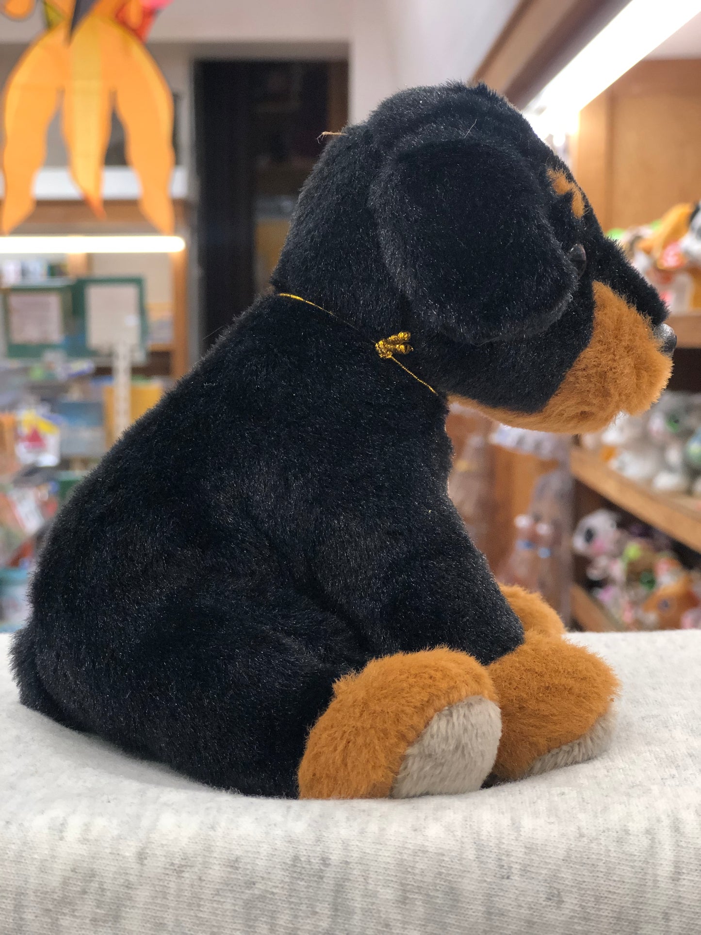 Soft Charlie Bears Cuddle Cub Rottie Dog plush toy for babies, black and tan, sitting on display in store