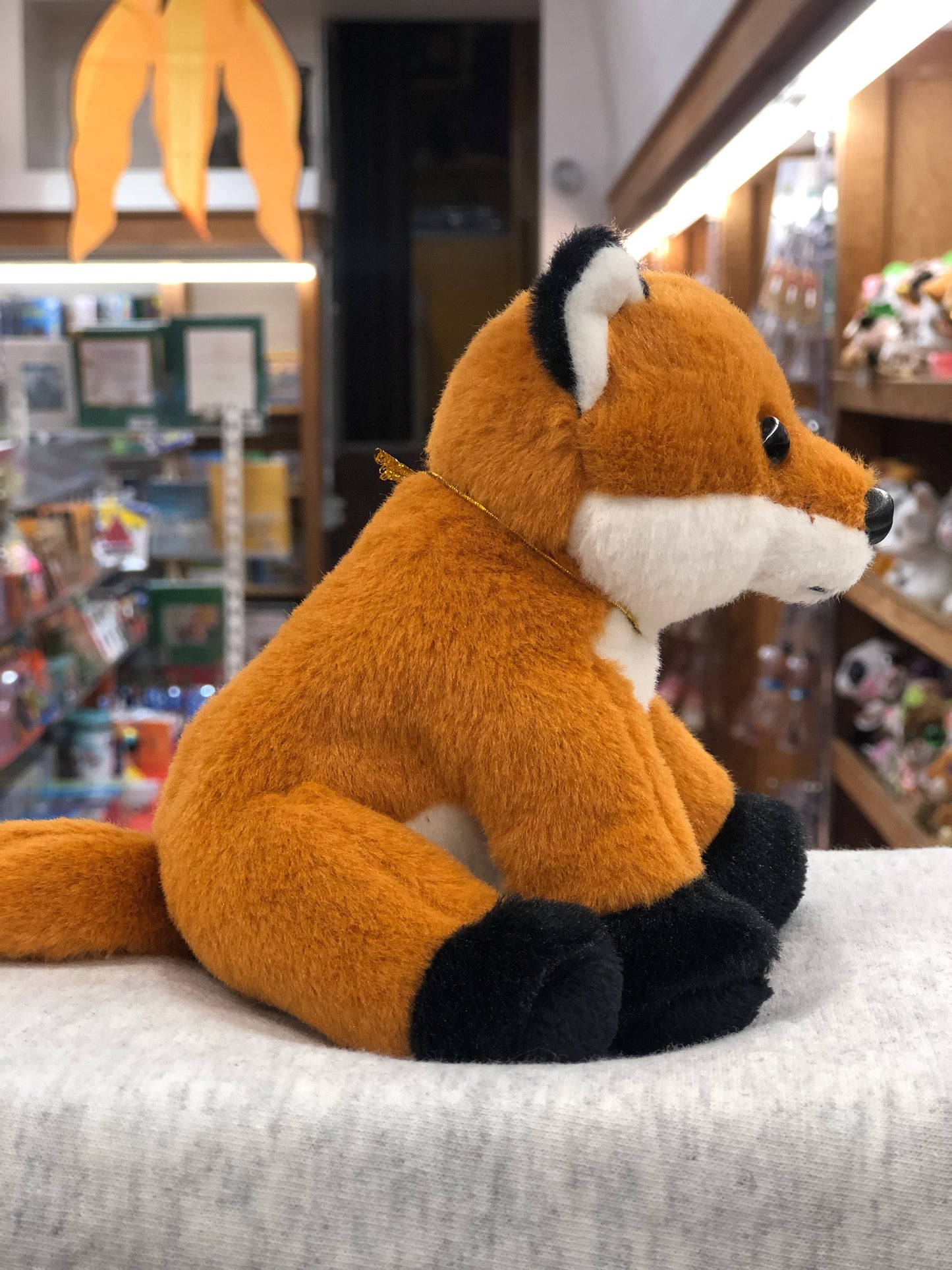 Soft and cuddly Charlie Bears fox plush toy for babies, displayed in a toy store with colorful background
