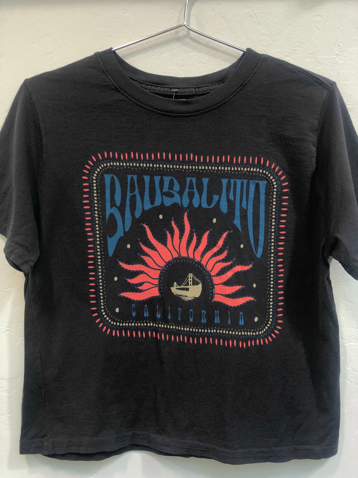Sausalito California crop top with retro sunburst design featuring Golden Gate Bridge icon, 70s-inspired graphic on black t-shirt
