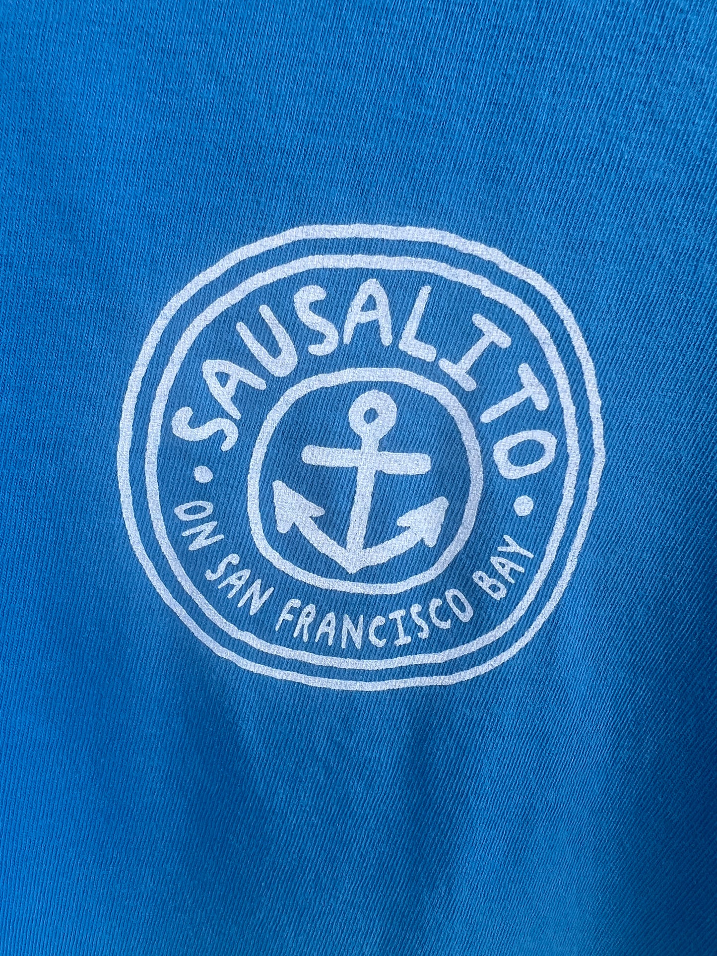 White logo with anchor on blue fabric.