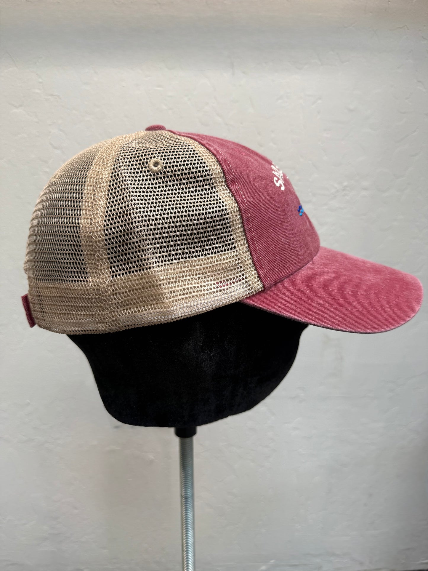 Sausalito trucker cap with brick-colored front, tan mesh back, and adjustable strap, displayed on stand