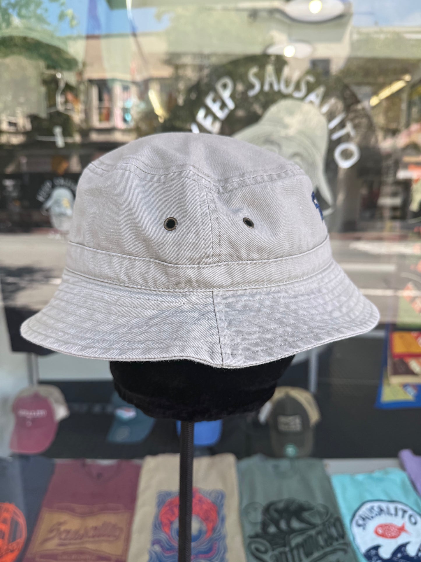 Light-colored bucket hat on a mannequin head displayed in front of a store window.