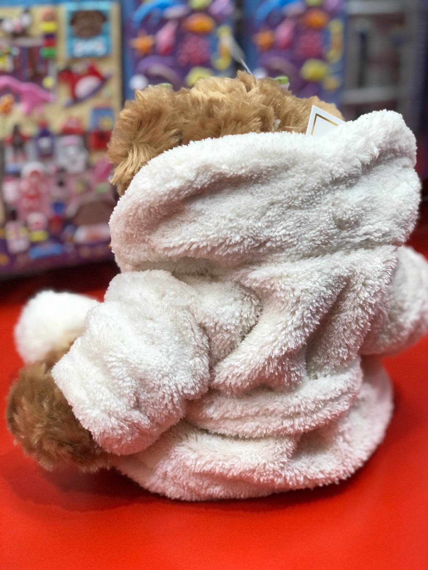 Cuddly Mr. Bukowski plush bear wearing soft white robe, perfect for relaxation and comfort, displayed in toy store setting