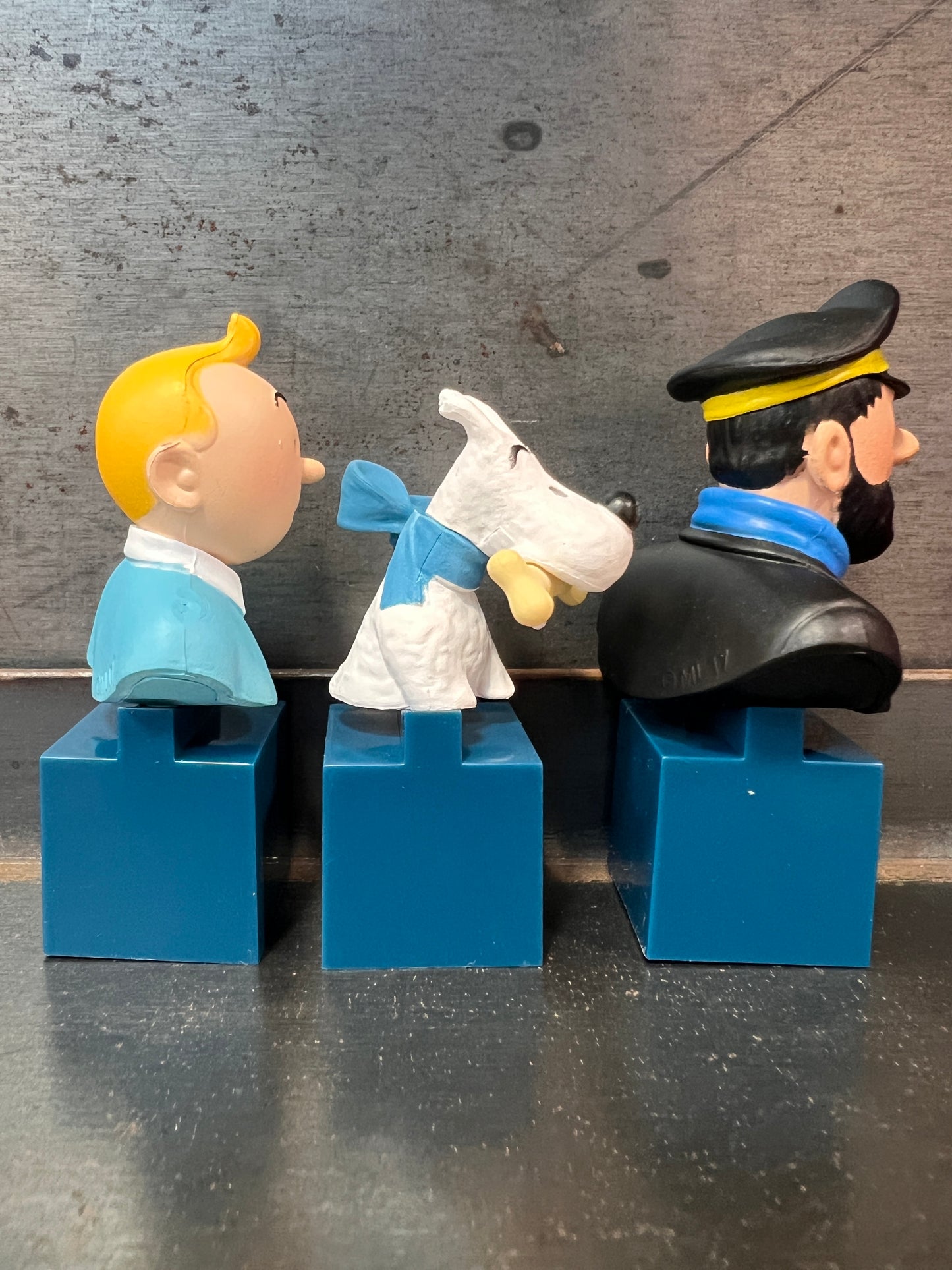 Tintin, Snowy, and Captain Haddock collectible bust set on blue stands, featuring colorful 7.5cm tall character figurines from The Adventures of Tintin
