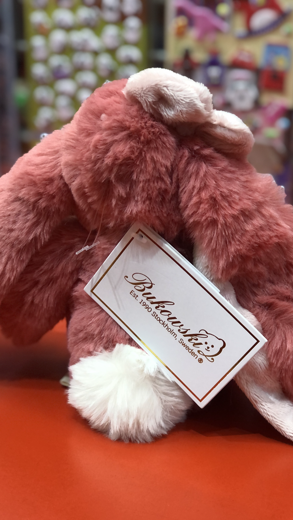 Soft pink Bukowski Bears bunny plush with long ears and fuzzy fur, perfect for cuddling, shown with brand tag