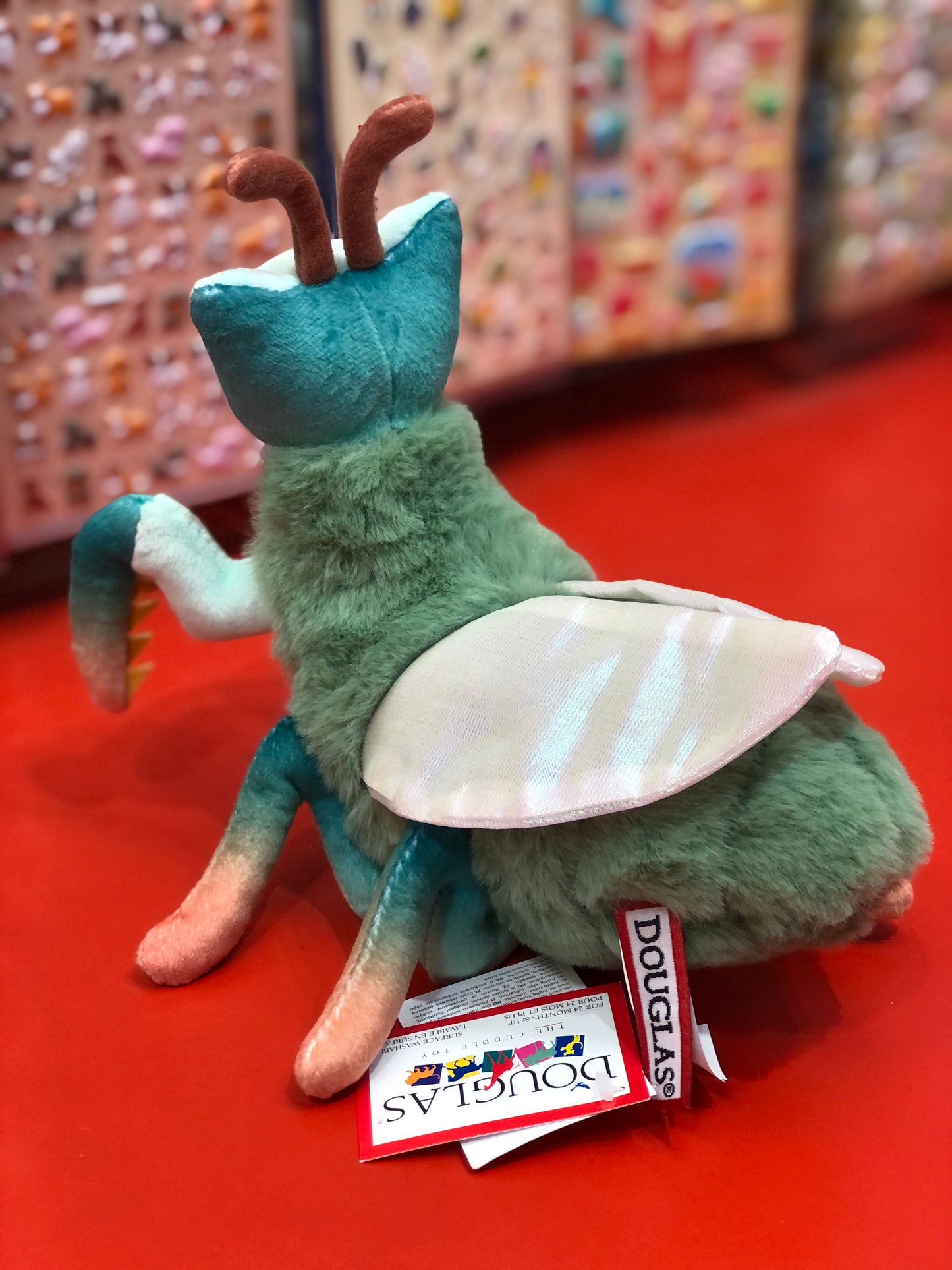 Plush insect toy with a Douglas tag on a red surface