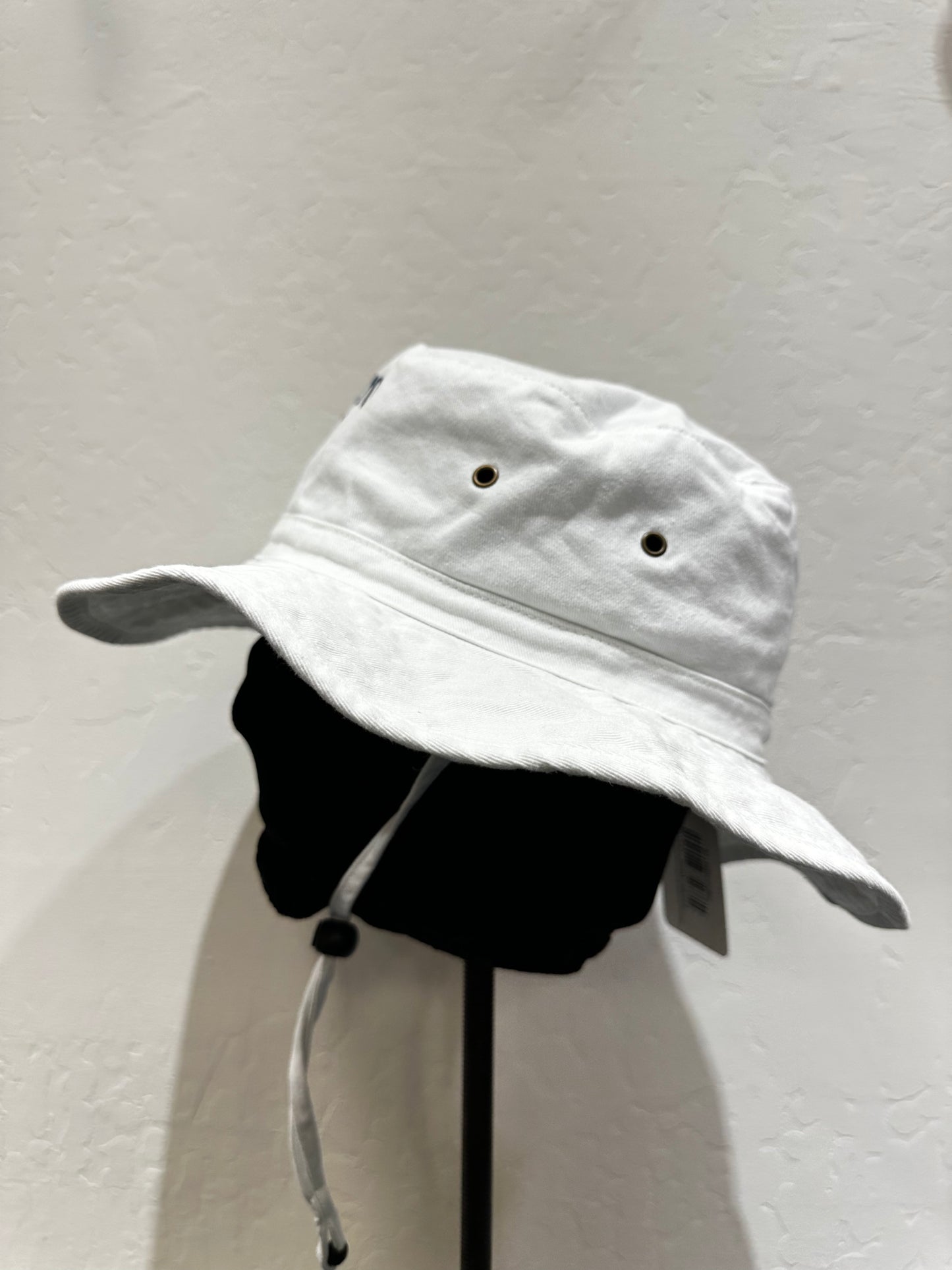 White washed cotton bucket hat with wide brim and adjustable chin cord, displayed on stand against light background