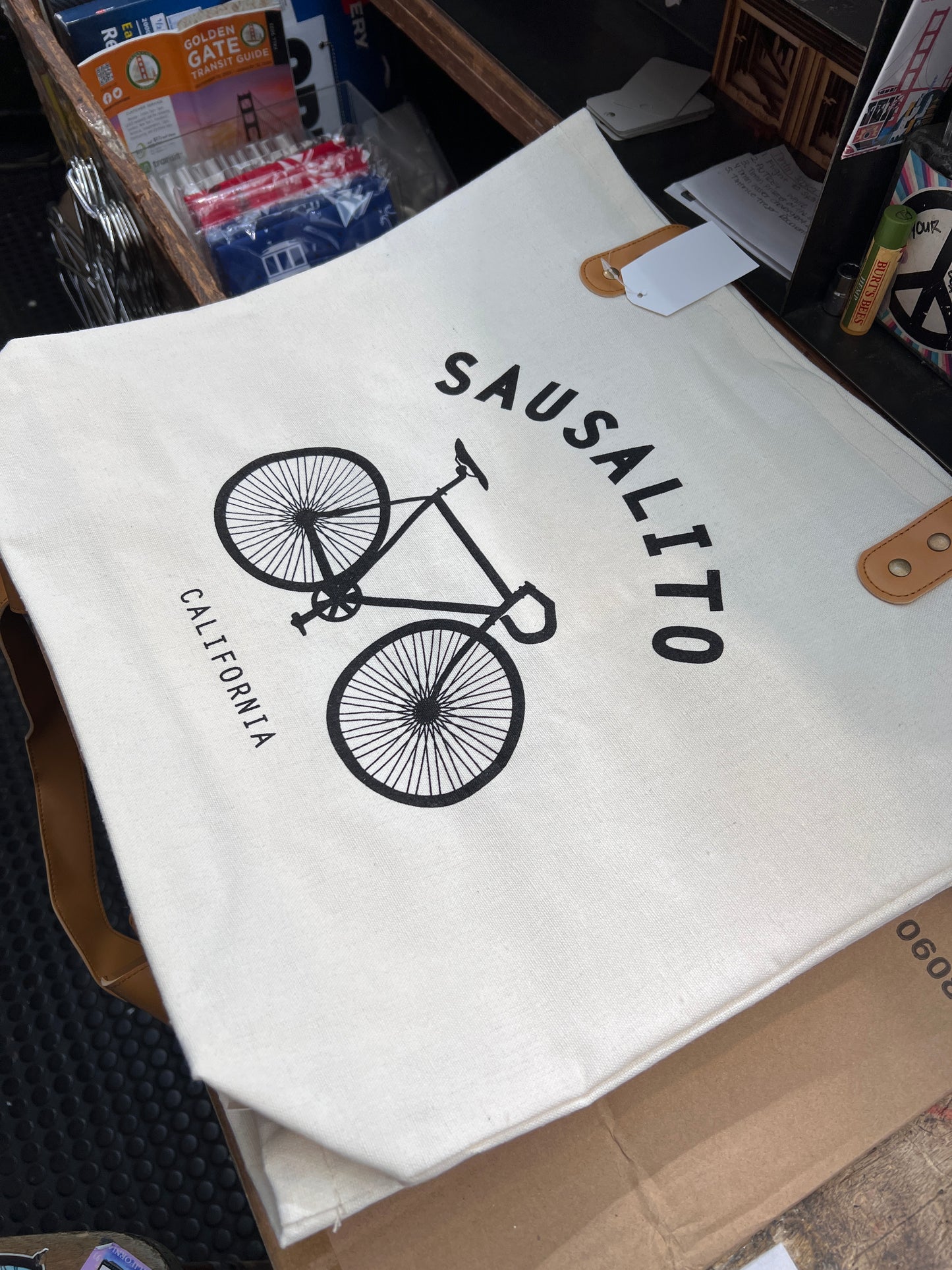 Sausalito bike bag with bicycle logo, surrounded by travel guides and accessories