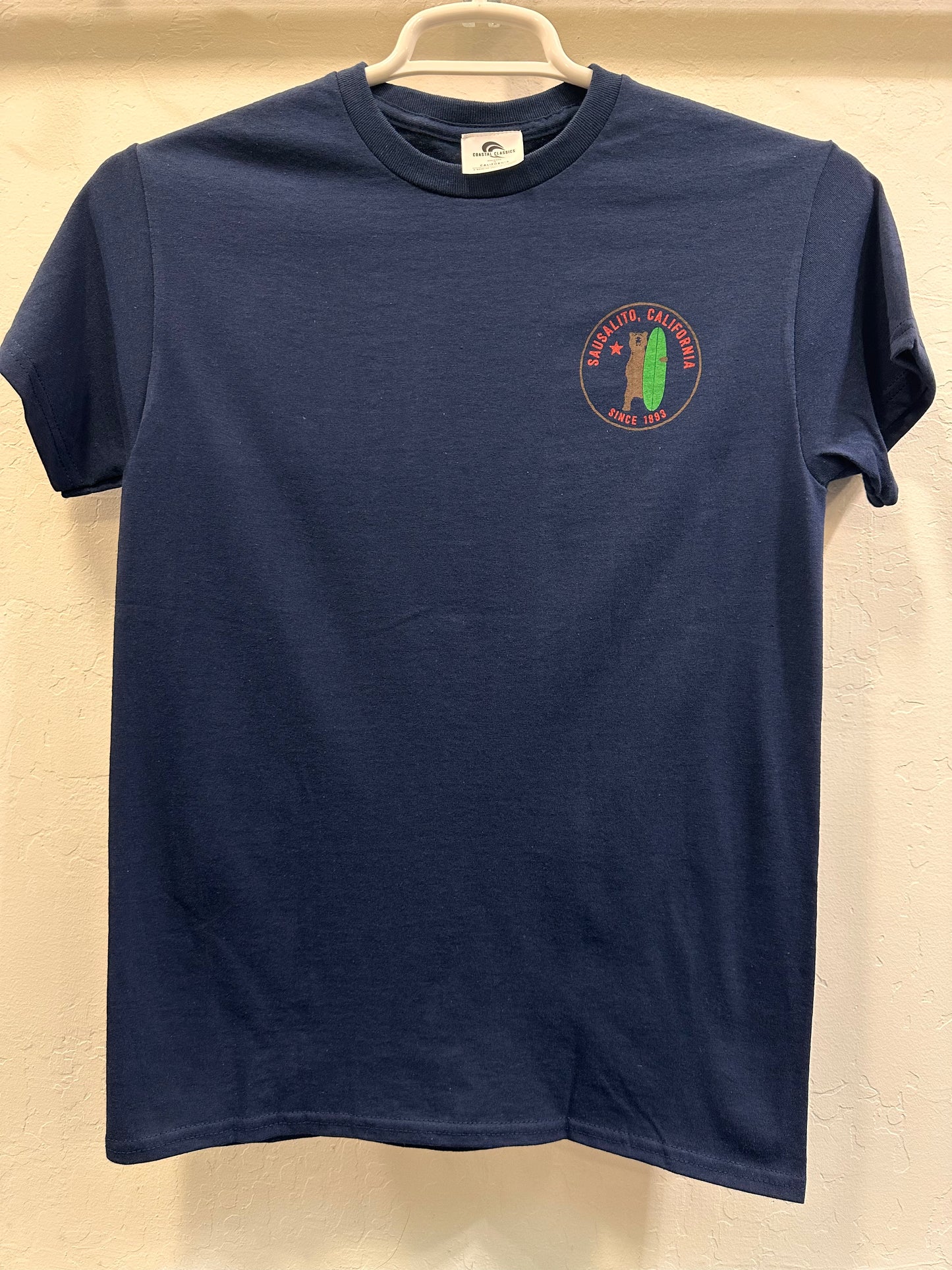Navy blue Sausalito Grizzly Surf t-shirt with circular logo featuring bear and surfboard, displayed on hanger