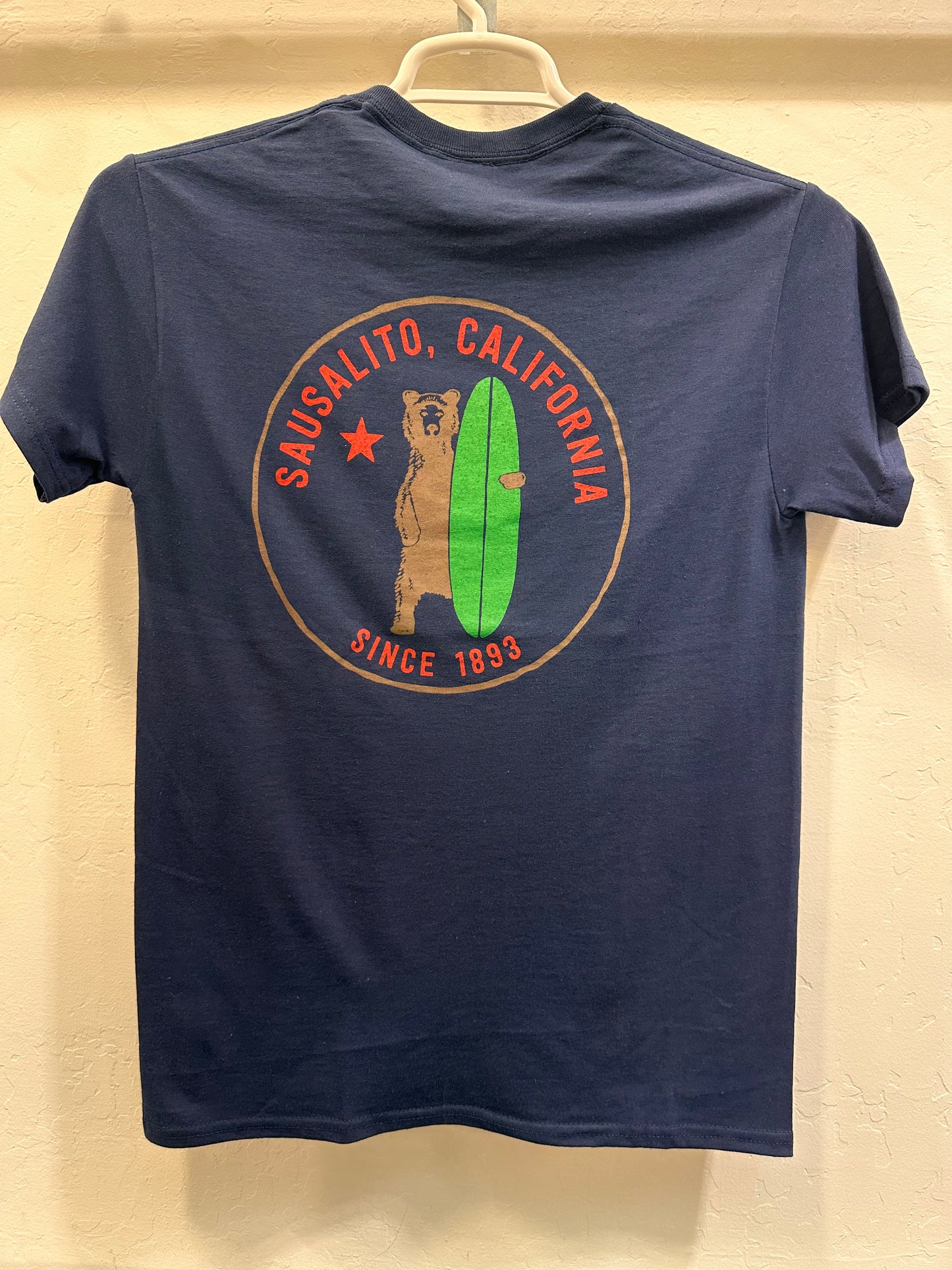 Navy t-shirt with Sausalito, California logo featuring surfing grizzly bear and green surfboard, established 1893