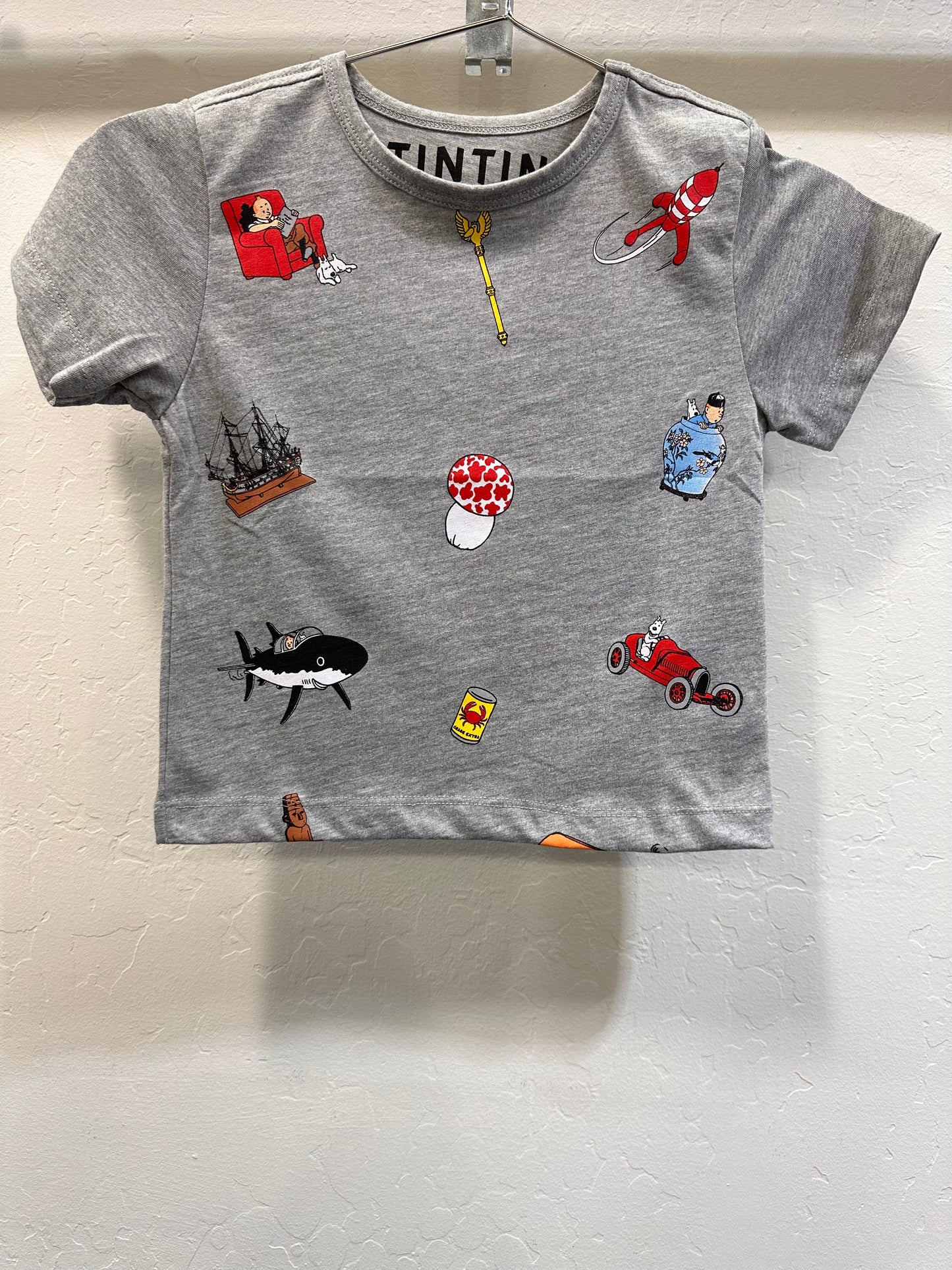 Gray kid's t-shirt featuring colorful Tintin-themed icons including rocket, car, ship, and characters from the popular comic series