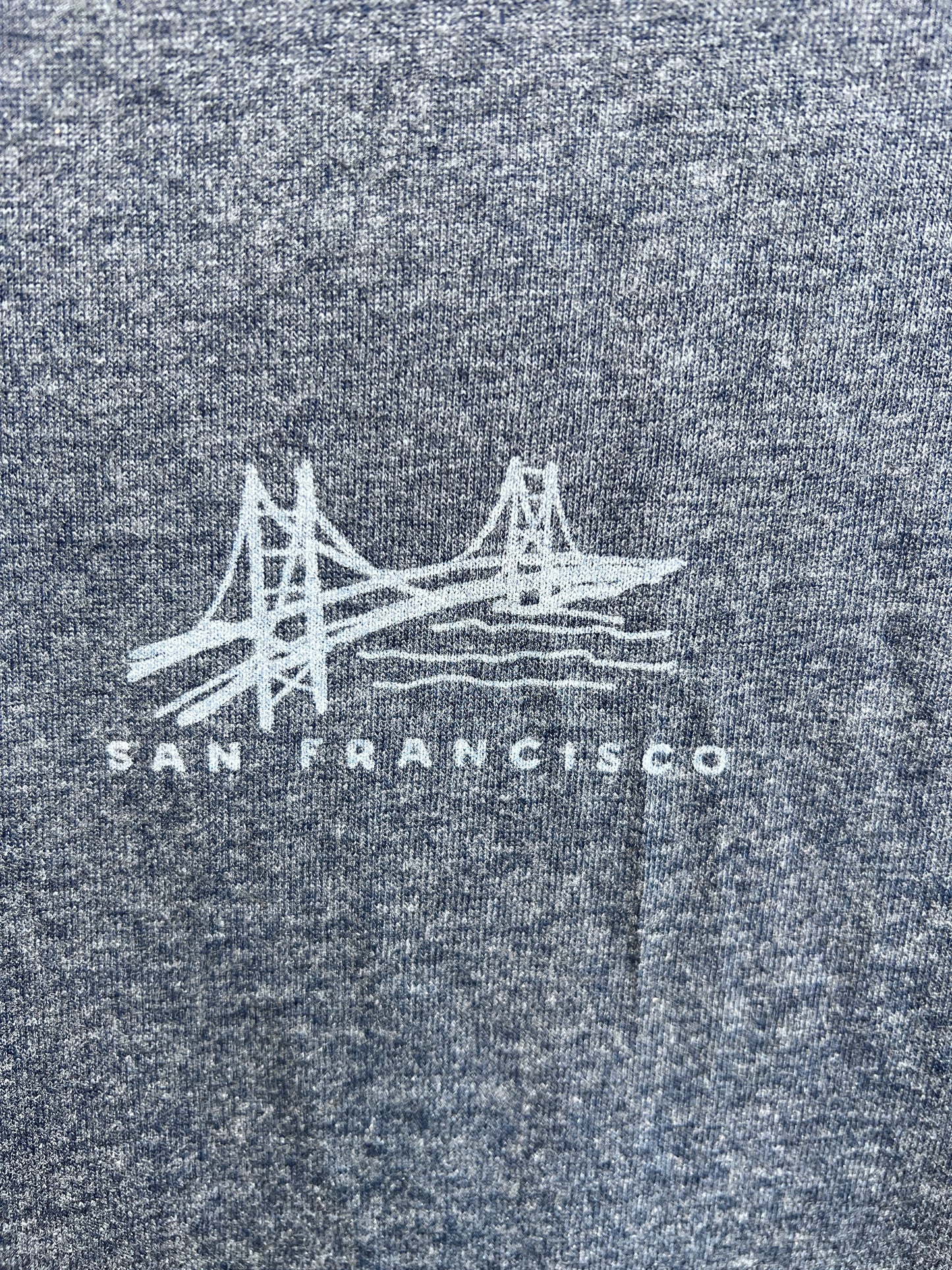 Golden Gate Bridge illustration on navy heather t-shirt with "San Francisco" text, showing front design of unisex shirt
