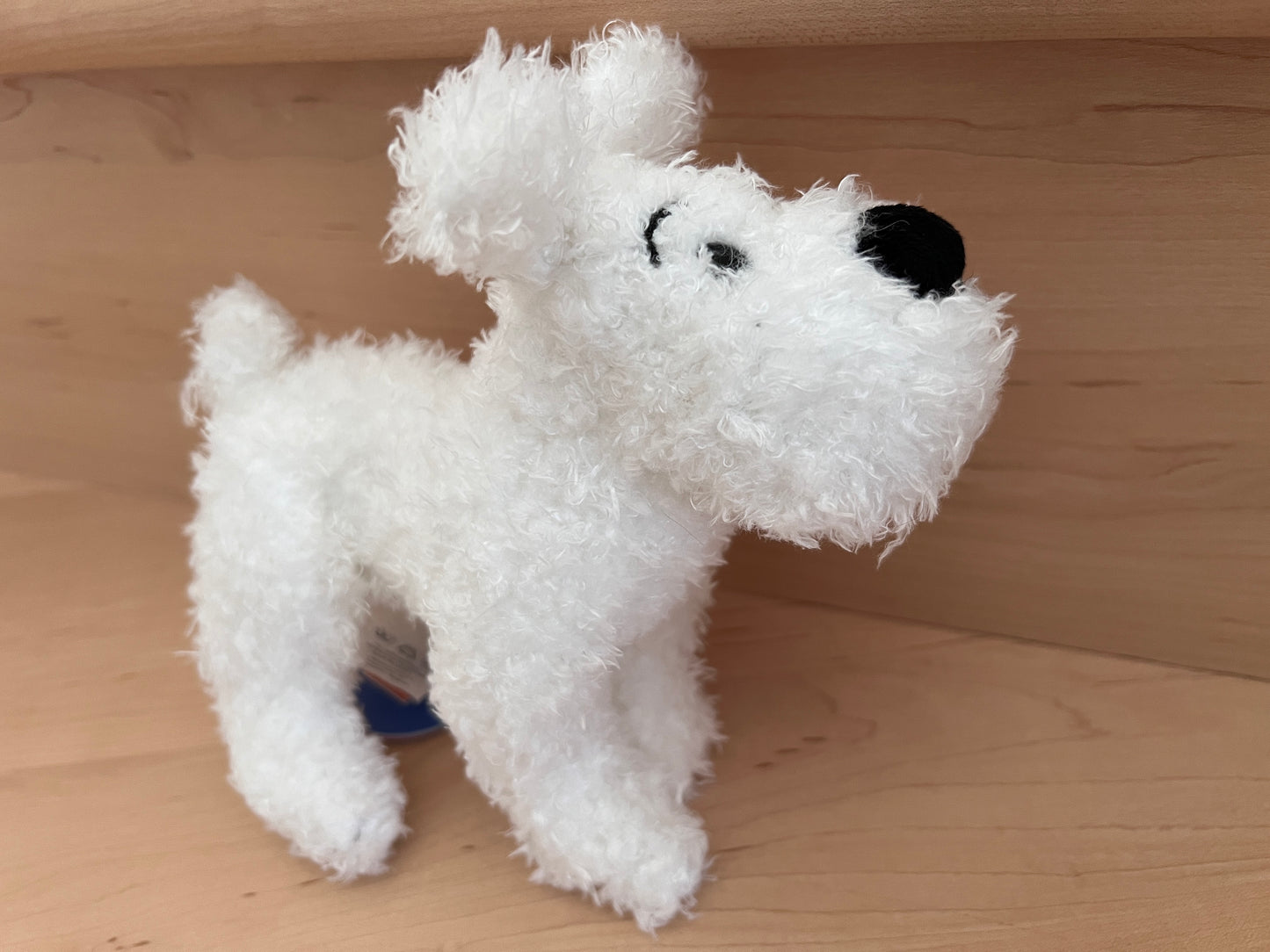 Soft white Snowy plush toy from Tintin, 8 inches long, with fluffy fur and black nose, on wooden surface