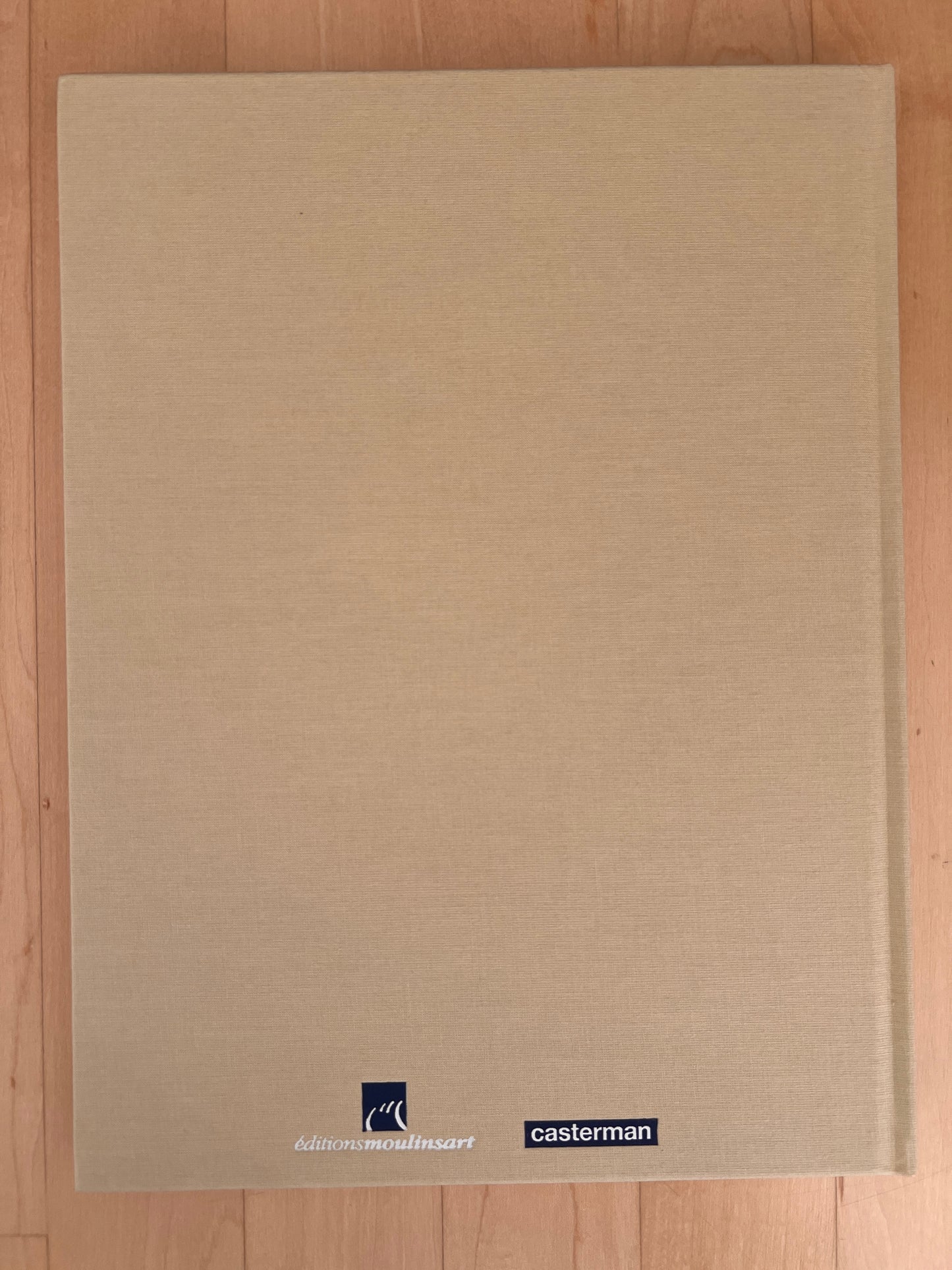 Tintin archive book 'Le Secret De La Licorne' by Moulinsart and Casterman, beige hardcover on wooden surface