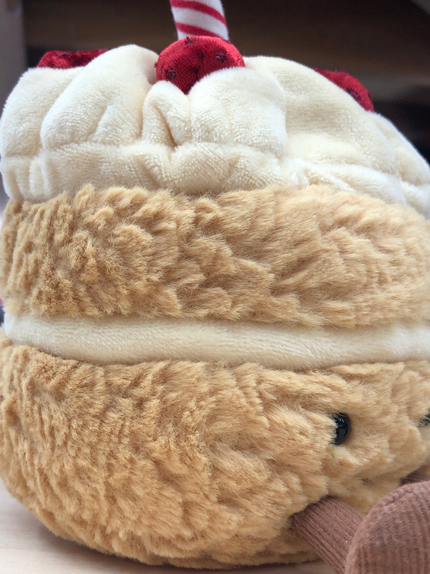 Jellycat Amuseables Birthday Cake plush toy with fuzzy tan body, white frosting, red strawberries, and striped candle on top