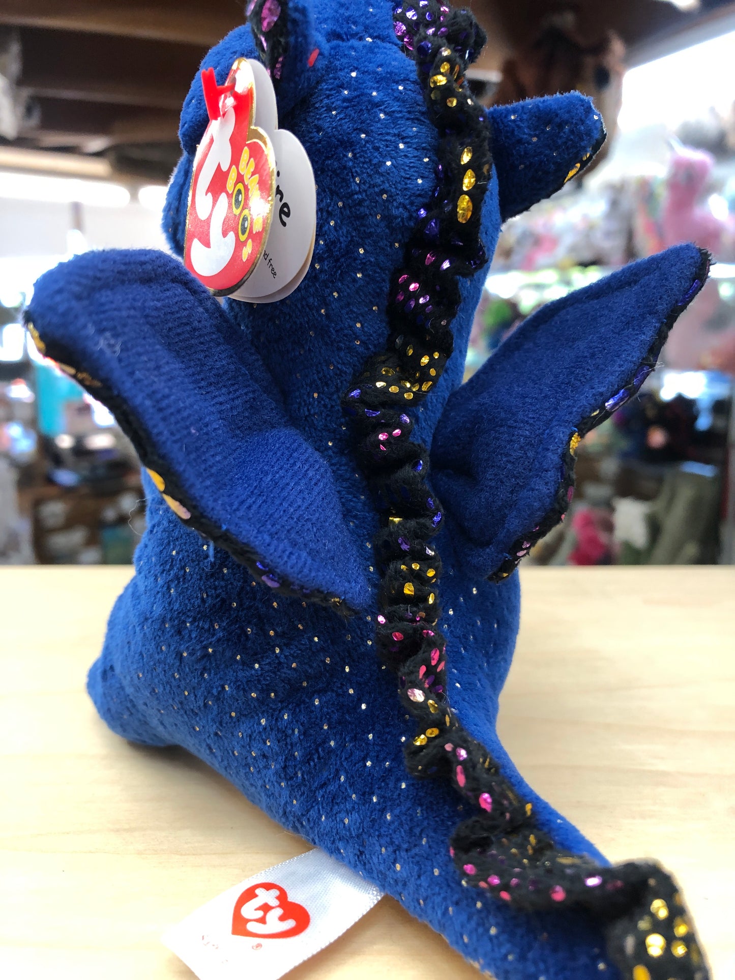 Ty Beanie Boo Saffire blue dragon plush toy with sparkly accents and tag, displayed on store shelf
