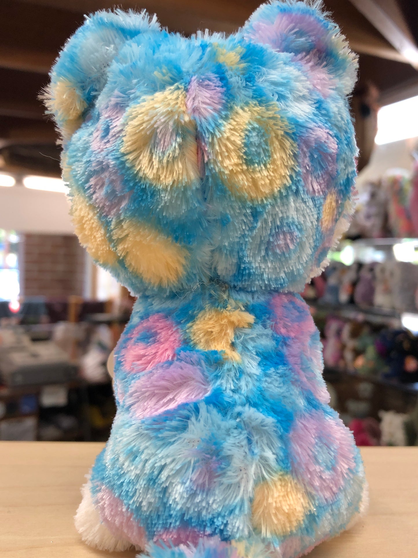 Ty Beanie Boo Helena Huskycorn plush toy with colorful tie-dye fur in blue, pink, and yellow, viewed from behind