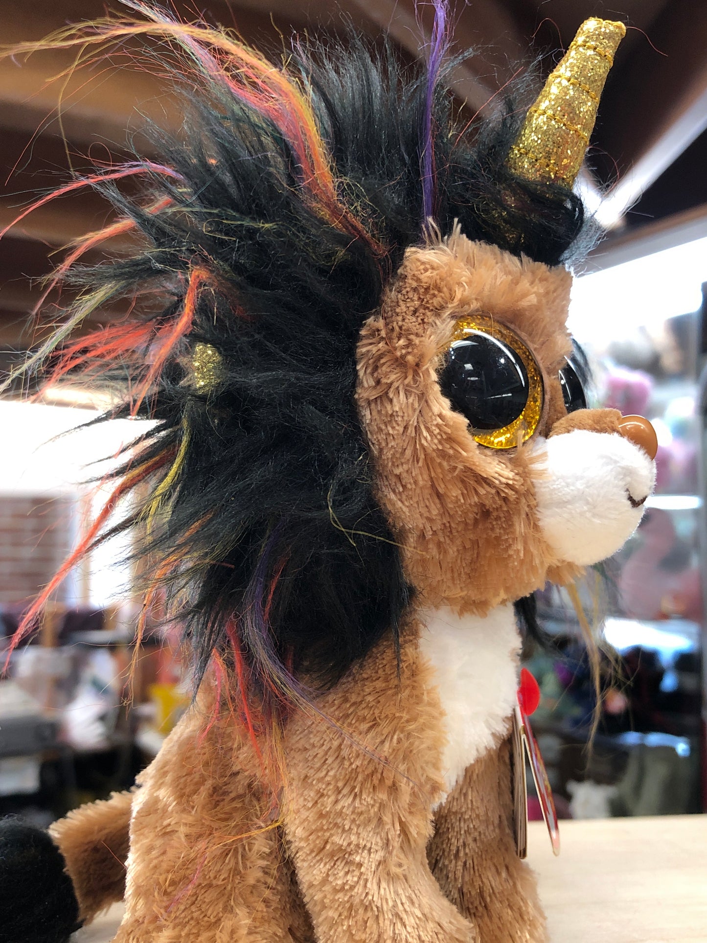 Ty Beanie Boo Ramsey Lion plush with colorful mane, glittery eyes, and golden horn, showcasing unique design and soft texture