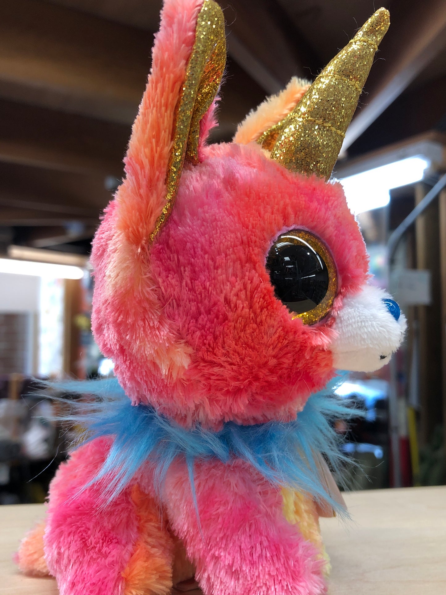 Colorful Ty Beanie Boo plush toy with pink fur, gold glittery horns, and large eyes, perfect for cuddling and collecting
