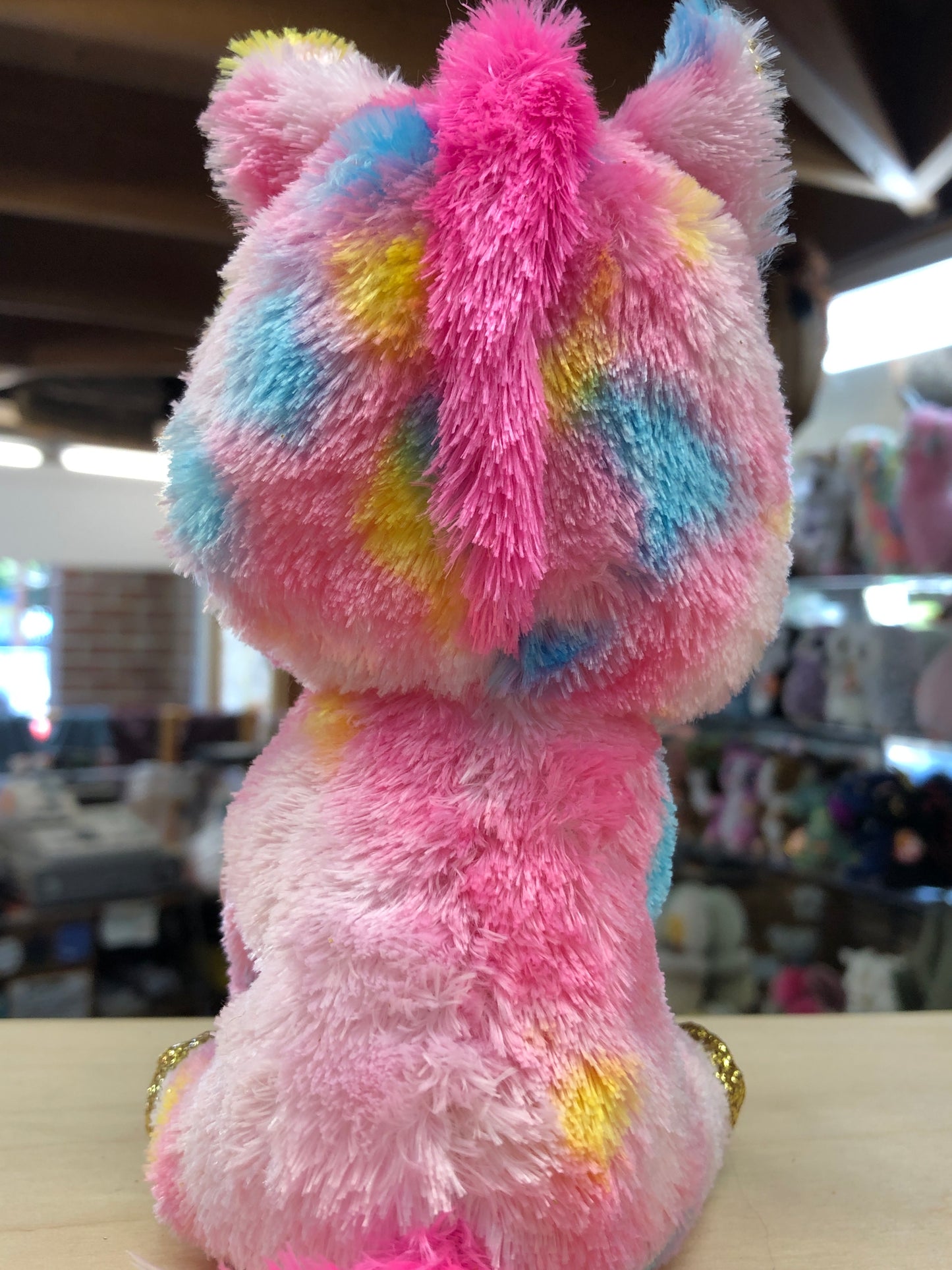 Colorful Ty Beanie Boo Fantasia unicorn plush toy with pink, blue, and yellow fur, gold hooves, and sparkly eyes on display
