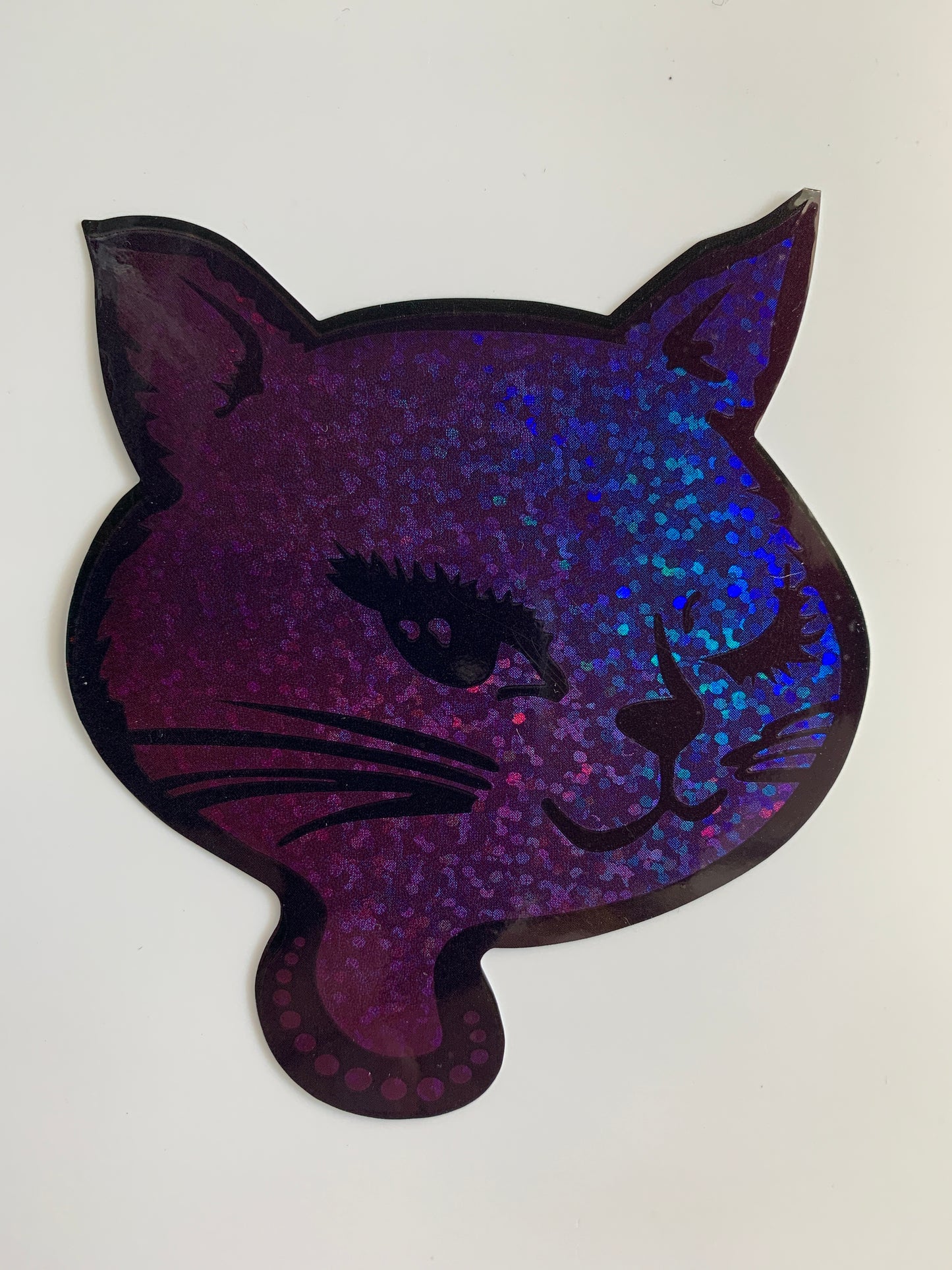 Purple glitter winking cat sticker with holographic effect, showcasing retro 90s design on durable mylar material