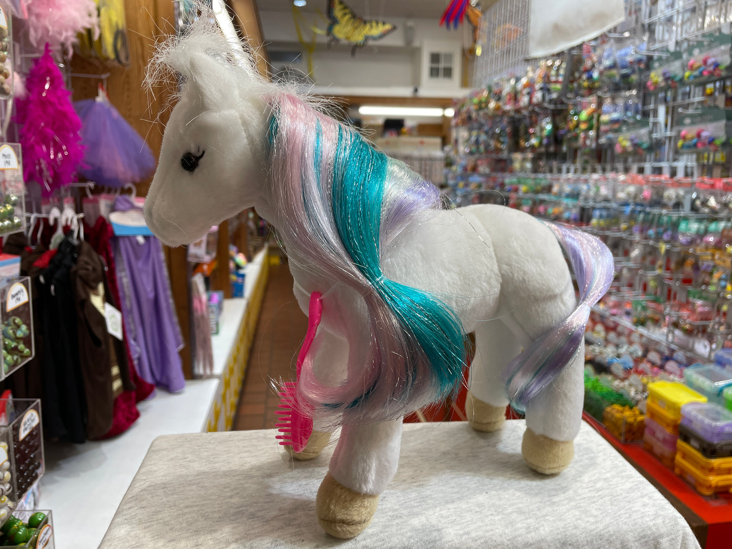 White plush unicorn toy with colorful mane and tail on display in toy store, showcasing Princess Unicorn stuffed animal