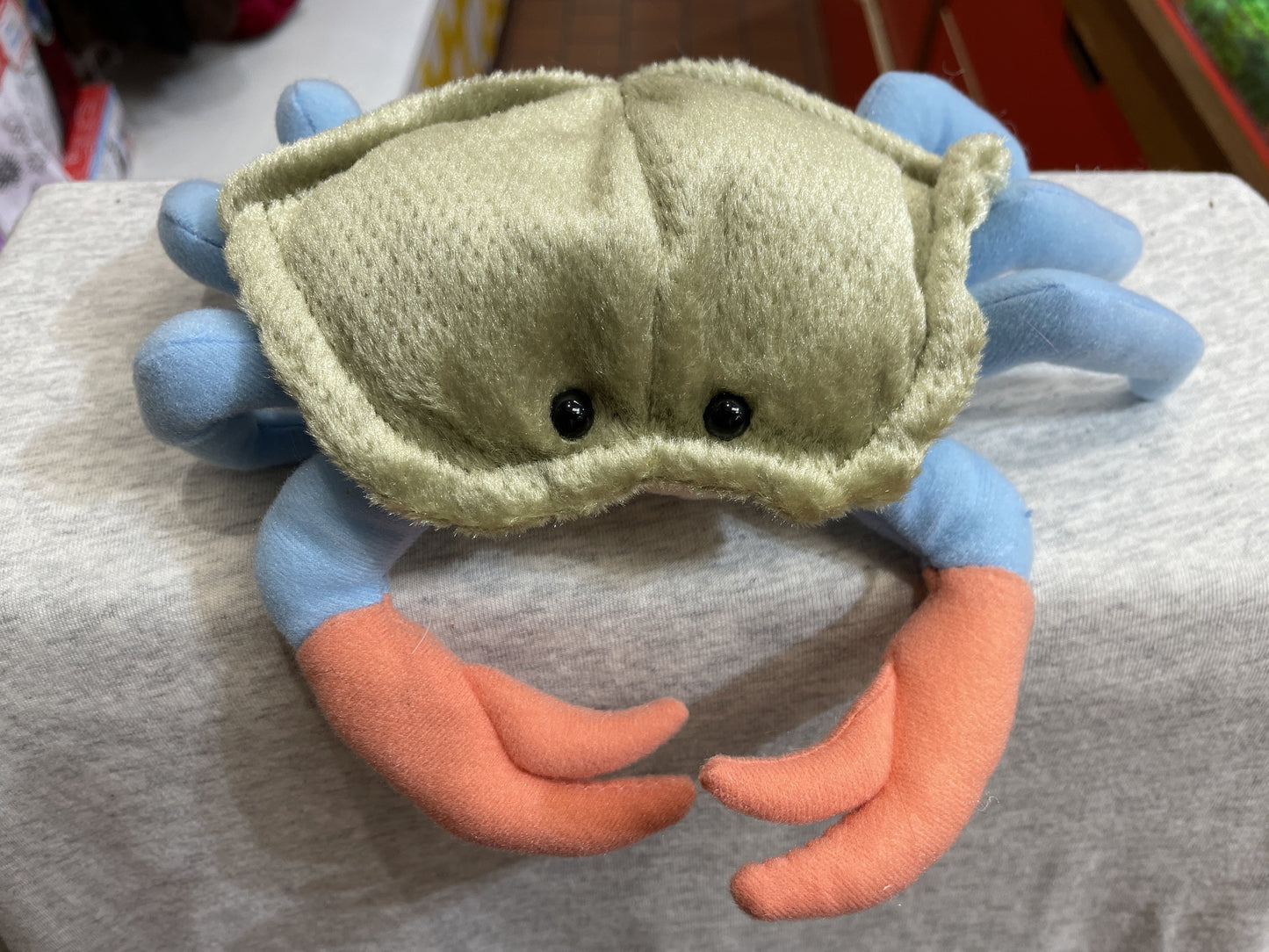 Cuddly blue crab plush toy with green shell, bright blue legs, orange claws, and shiny black eyes, perfect for undersea adventures