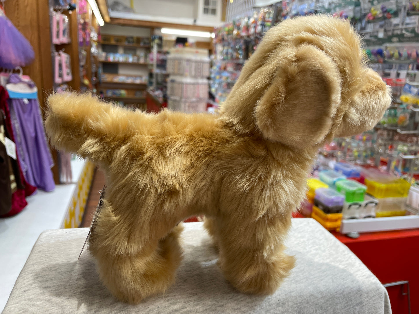 Soft golden retriever plush toy on display in toy store, featuring floppy ears and realistic fur texture
