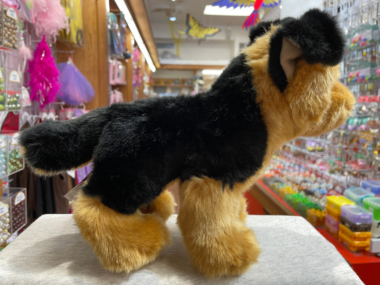 Realistic German Shepherd plush toy with black and tan fur standing in toy store display, showcasing lifelike details and soft texture
