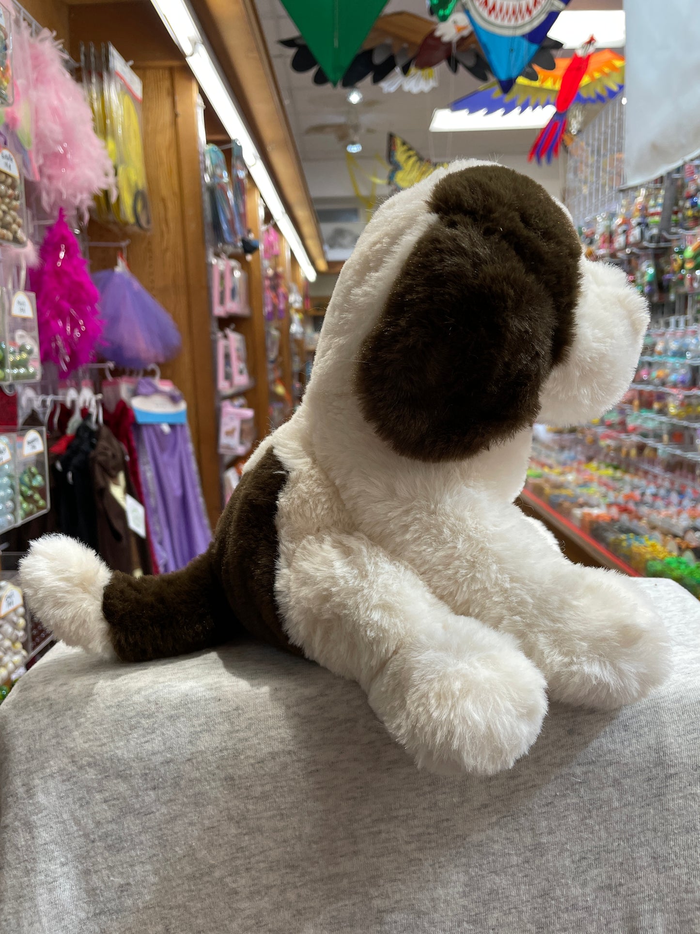Cuddly Douglas Softie Donnie puppy plush toy with floppy ears and brown spots, sitting in colorful toy store display
