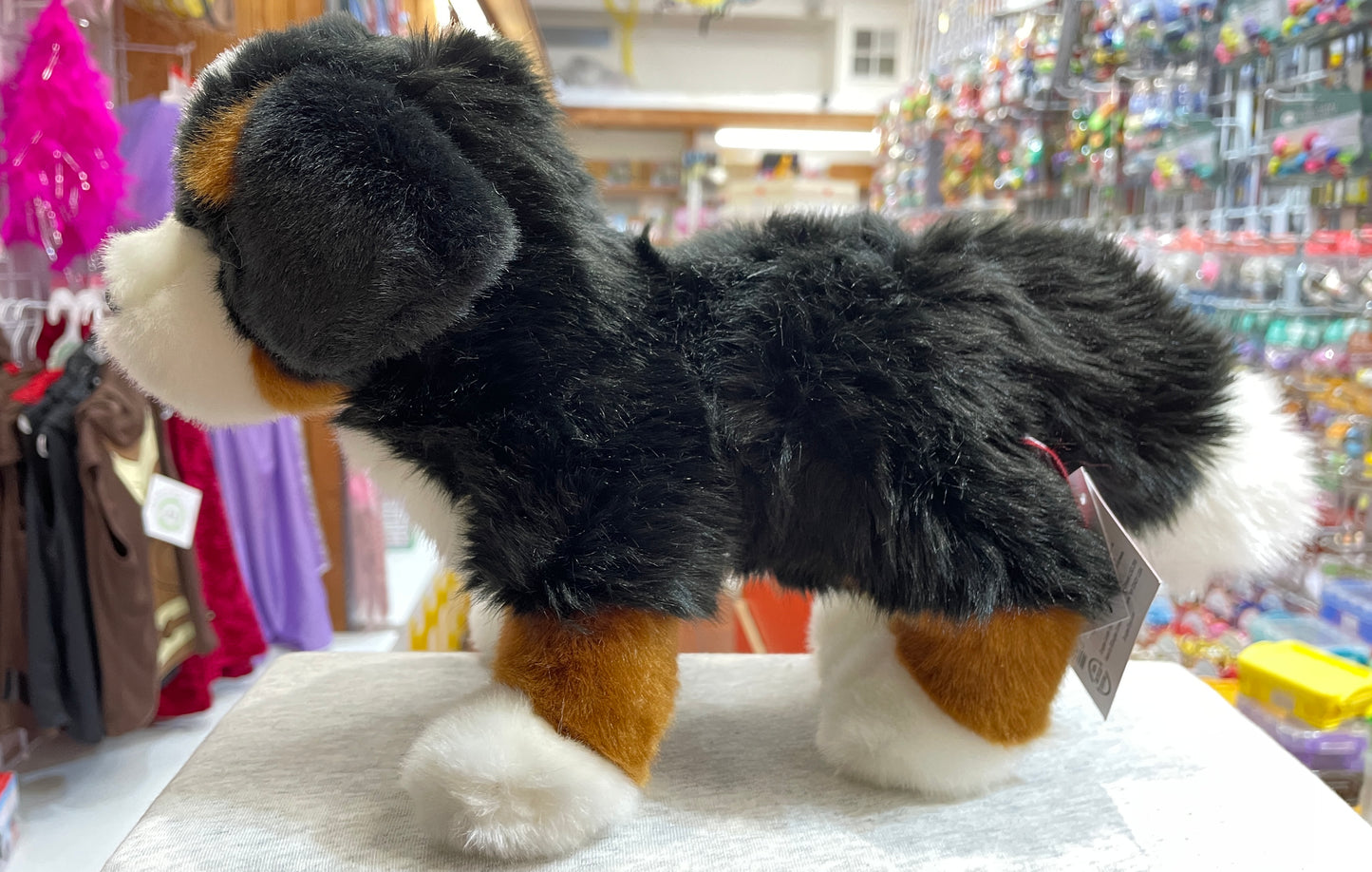 Realistic Bernese Mountain Dog plush toy with tri-color coat in toy store display, showcasing soft fur and authentic breed details