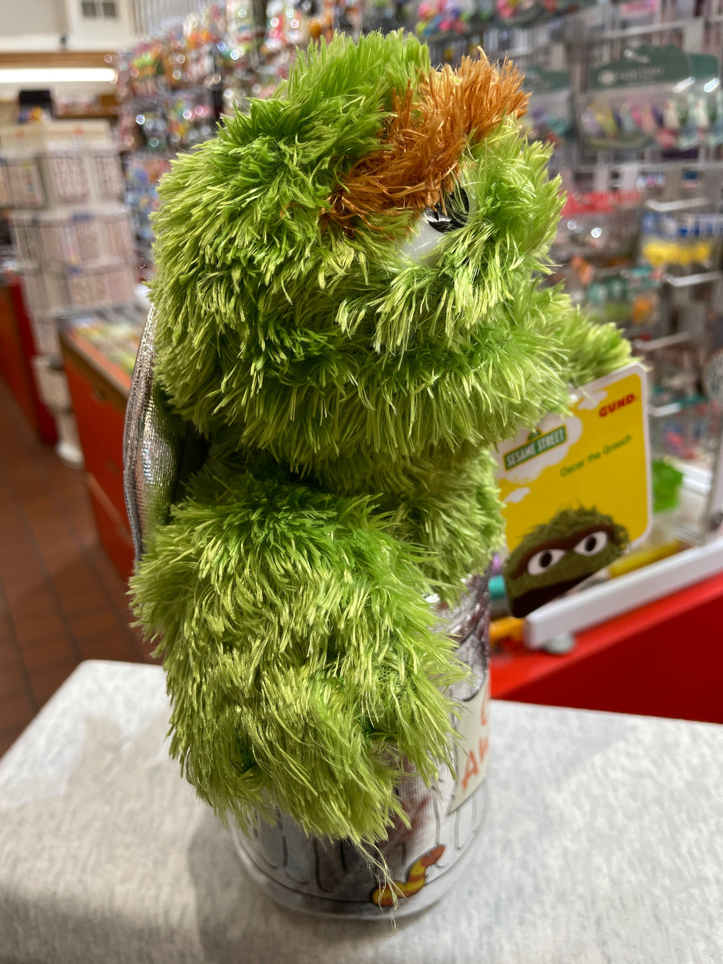 Gund Sesame Street Oscar the Grouch plush toy in store display, showing green furry texture and signature grumpy expression