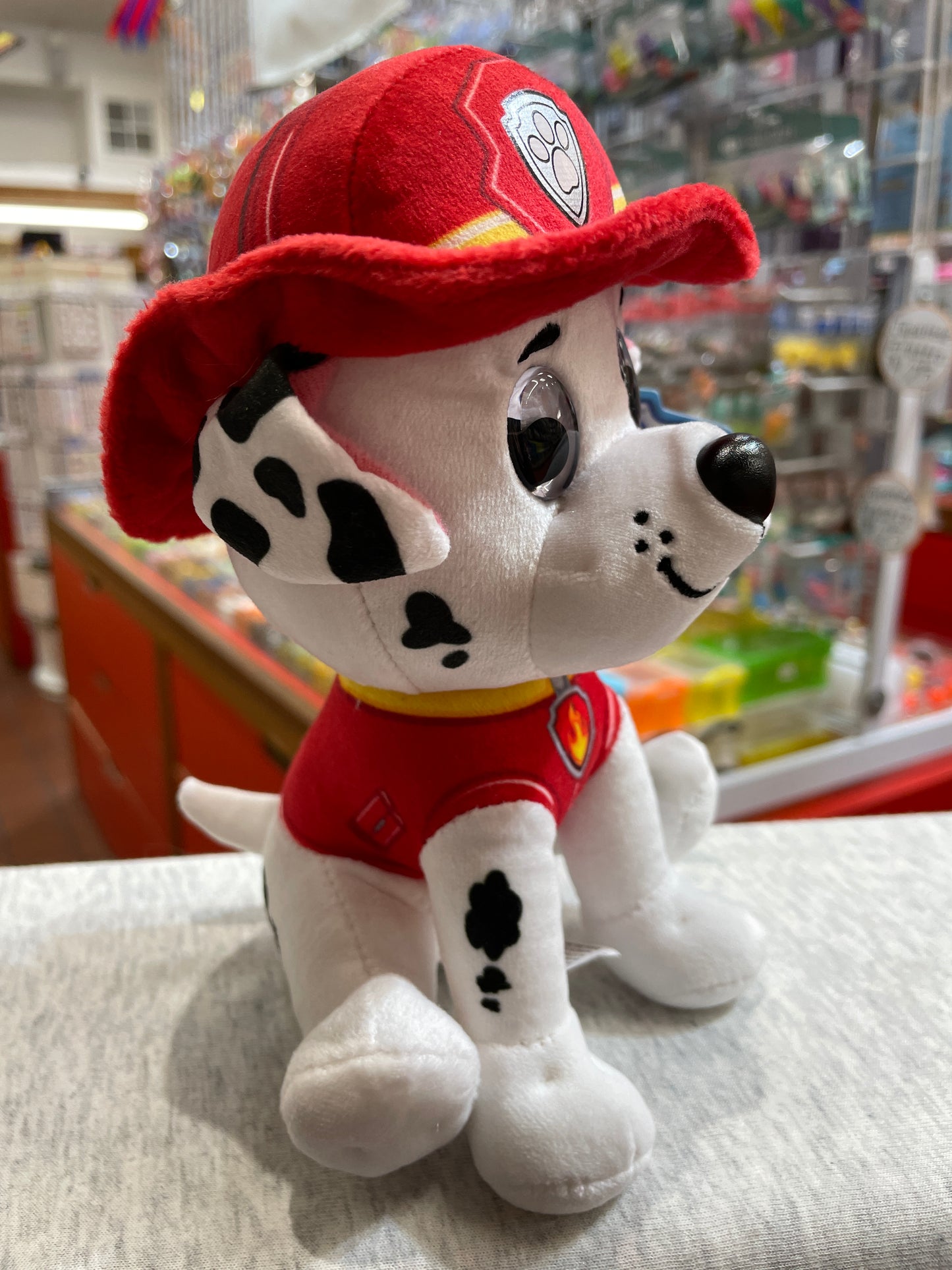 Gund Paw Patrol Marshall plush toy, dalmatian puppy in red firefighter uniform and hat, sitting in toy store display