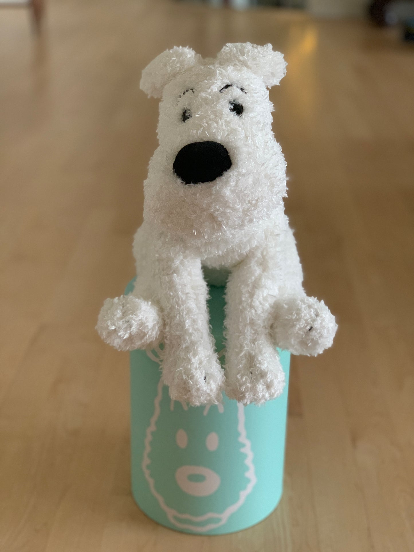 Soft, cuddly 14.5" Snowy plush toy sitting on teal gift box, white fur and black nose, perfect for hugging