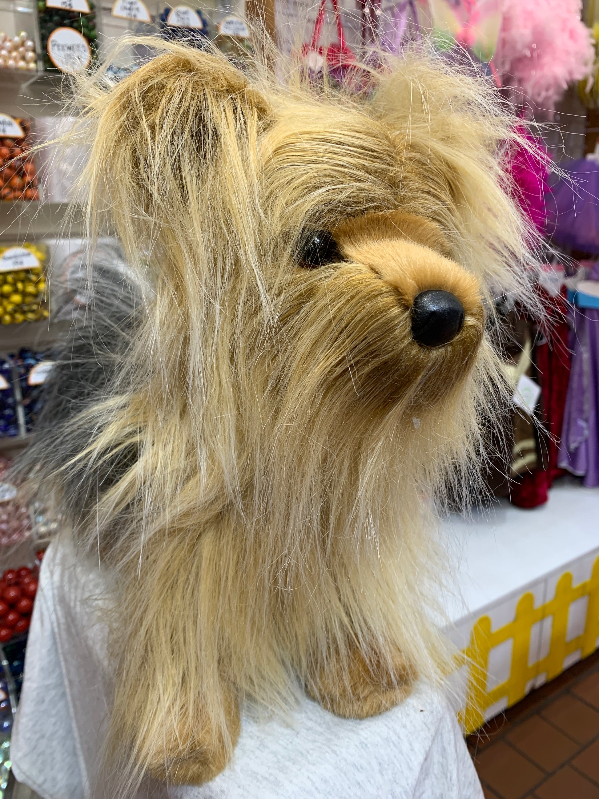Lifelike Yorkie plush toy with long, fluffy tan fur, expressive eyes, and upright ears, displayed in a store setting