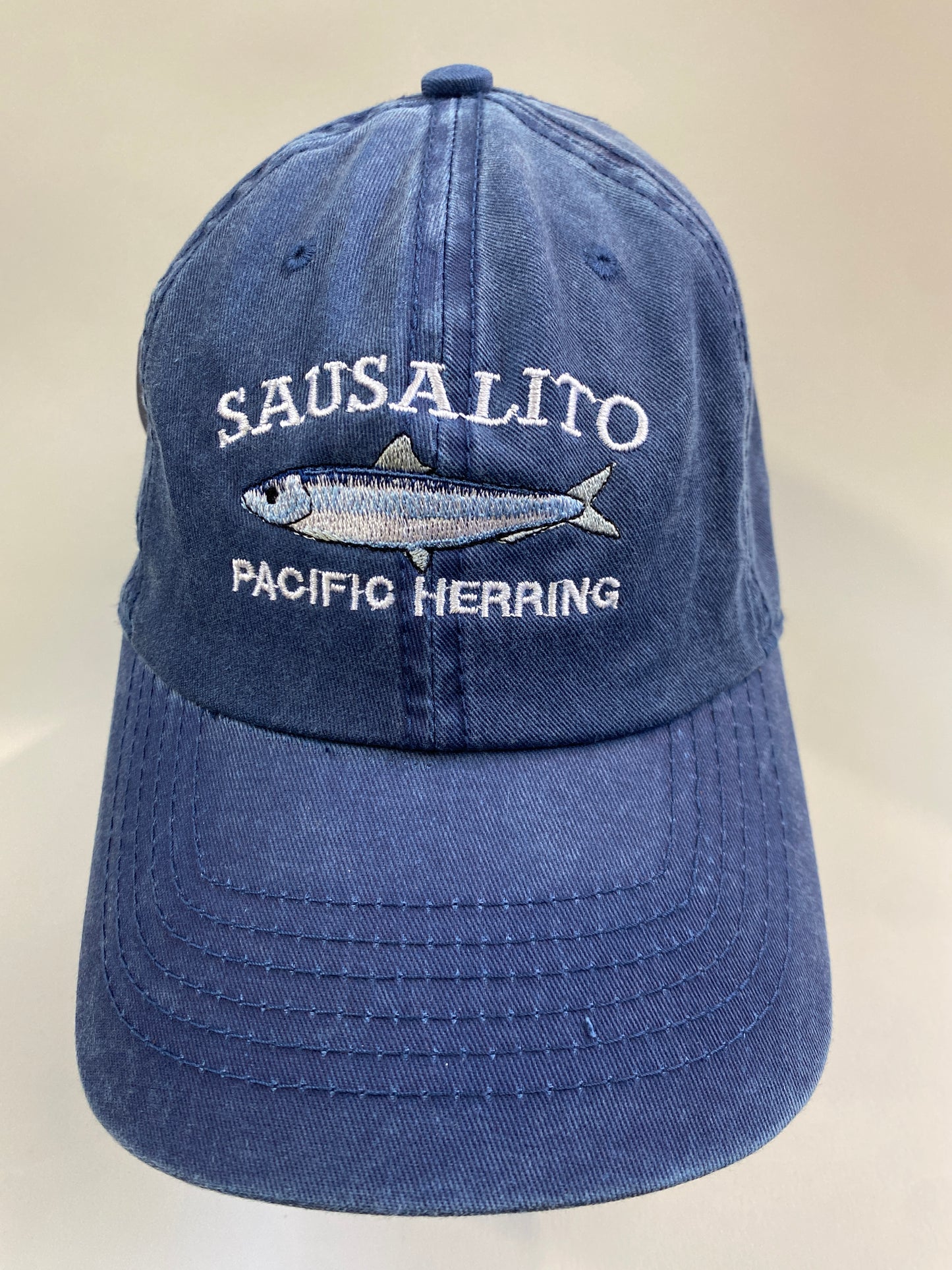Blue cotton cap with embroidered Sausalito Pacific Herring design, showcasing local marine life and coastal culture