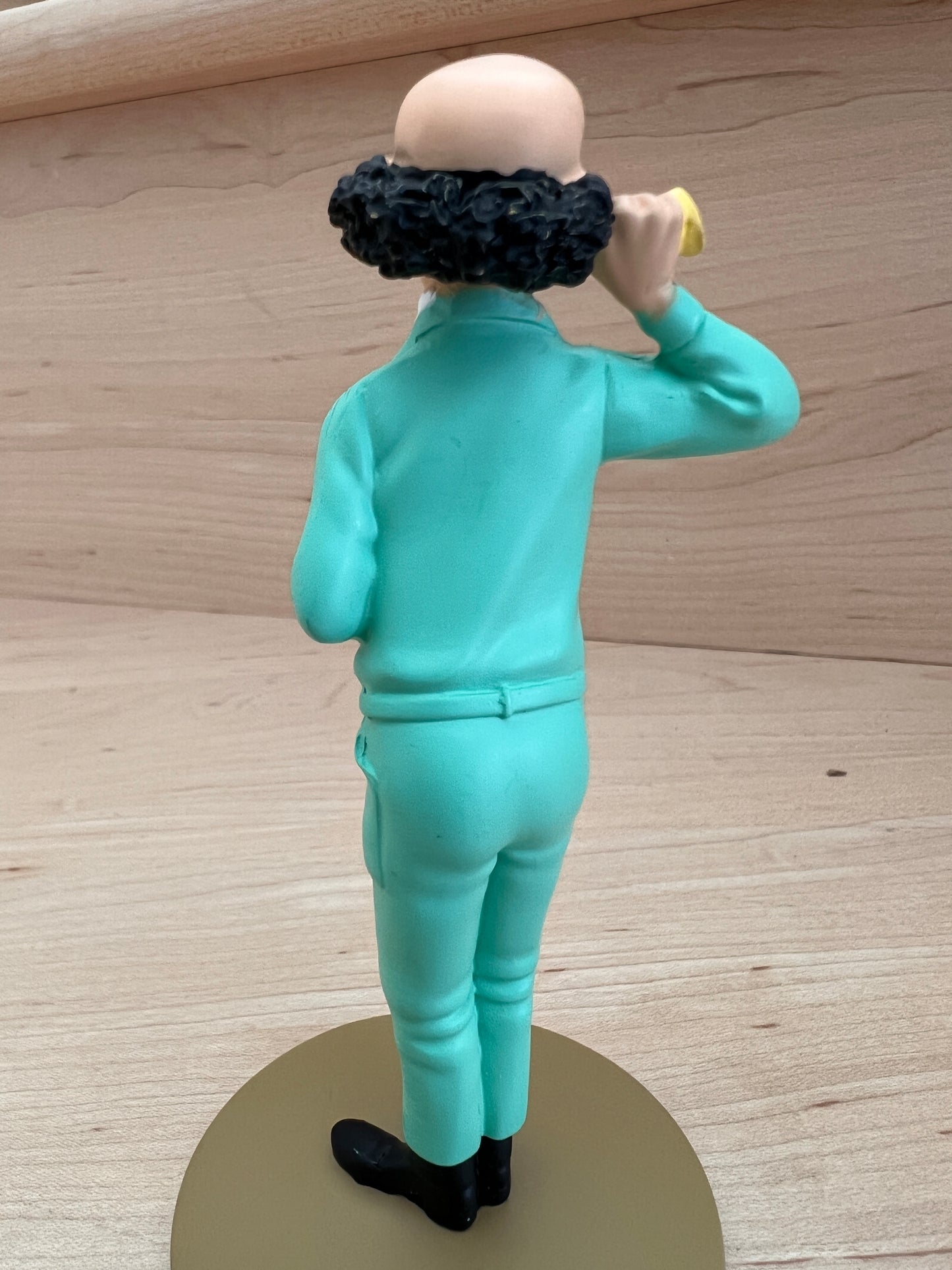 Professor Calculus resin figure in teal outfit, holding ear horn, standing on round base, viewed from behind