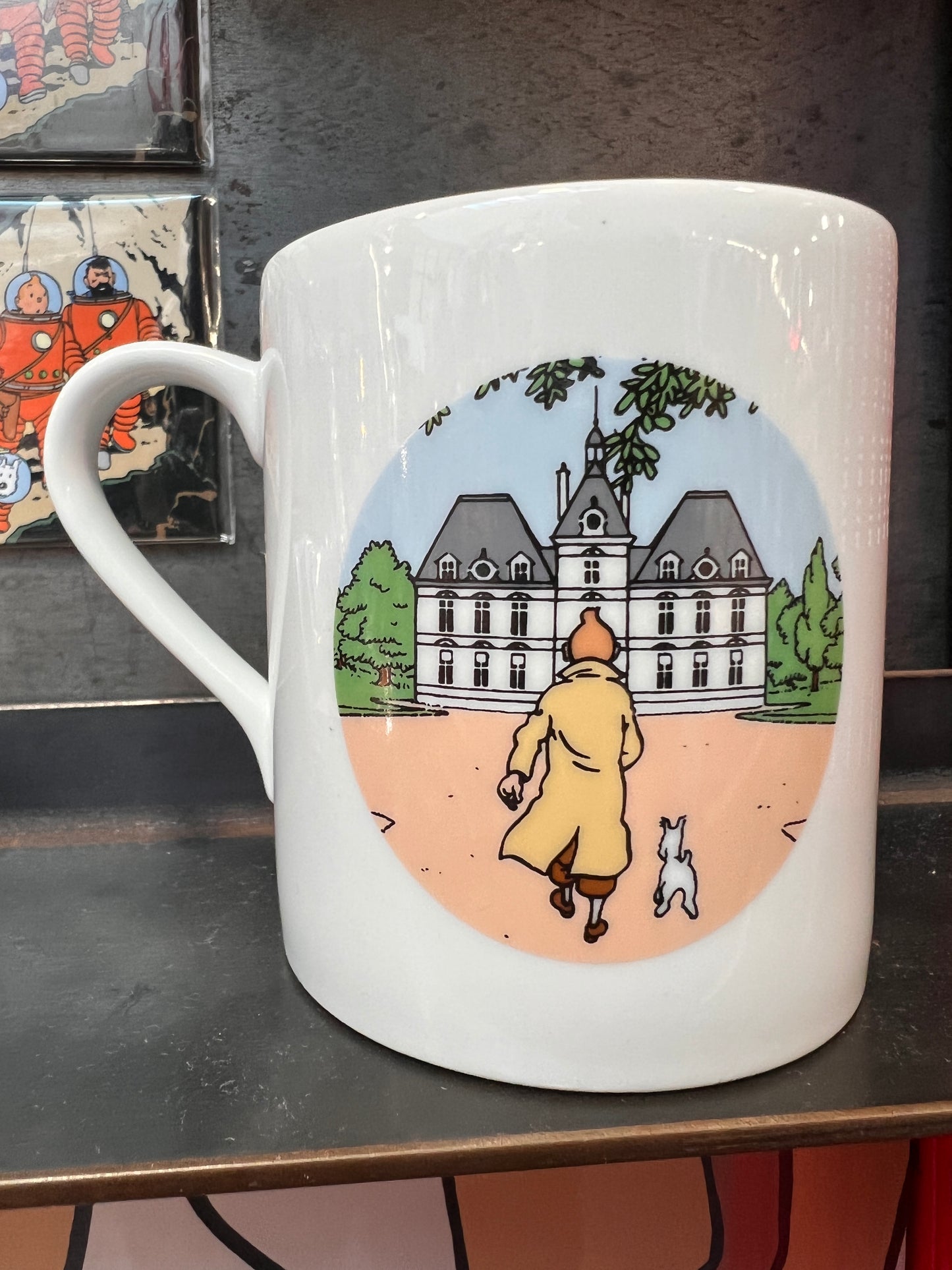 Moulinsart Castle mug featuring cartoon character in trench coat approaching mansion with small dog, collectible Tintin merchandise