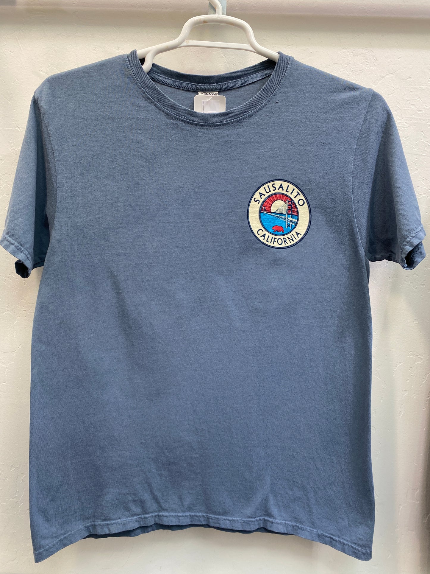 Blue Sausalito California t-shirt with Golden Gate Bridge logo patch, hanging on white hanger